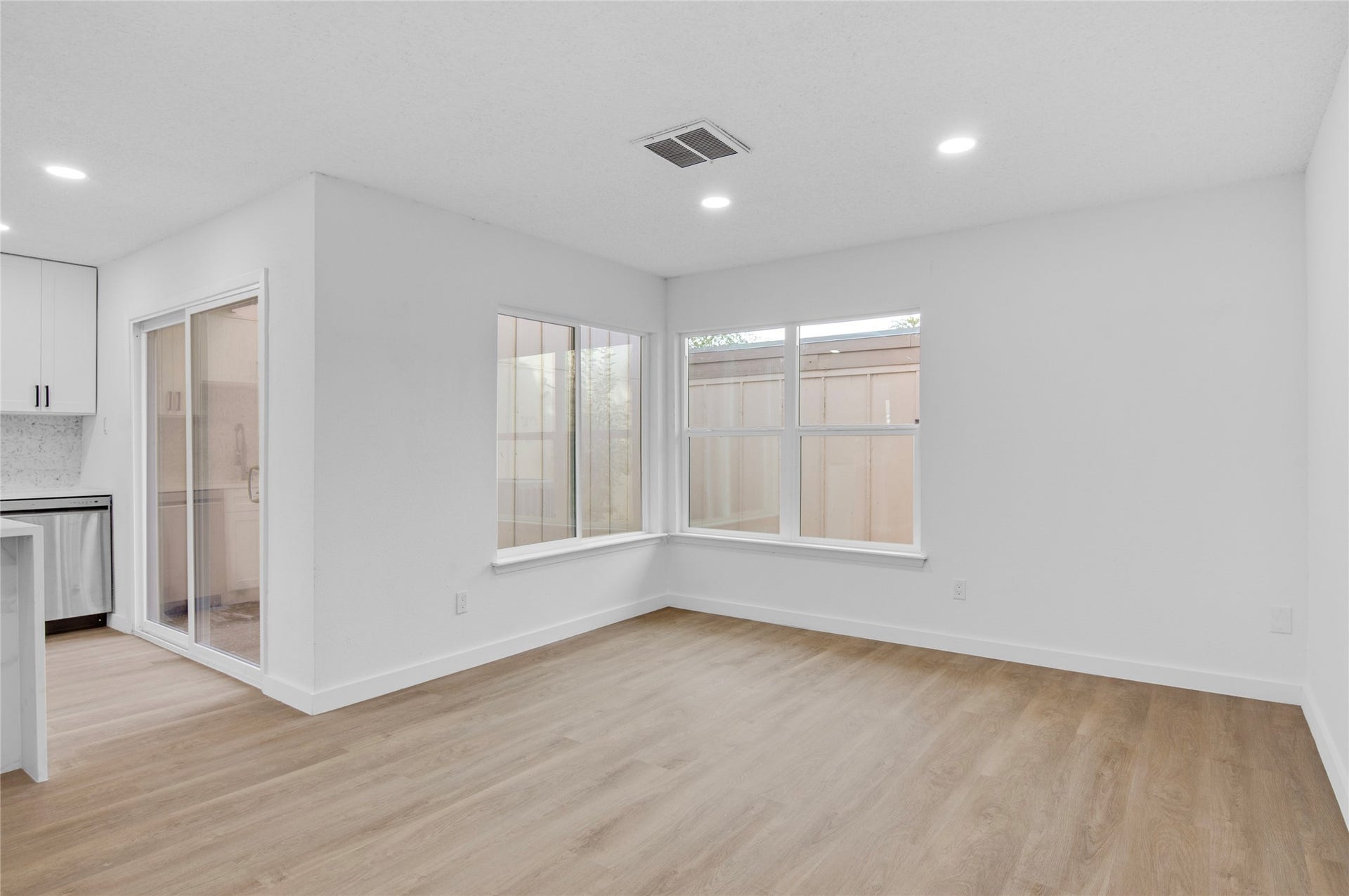 2916 Windchase Blvd, Houston, TX 77082 Bright and inviting living area with sleek wood flooring, recessed lighting, and large windows offering ample natural light, seamlessly connecting to a modern kitchen with stainless steel appliances.