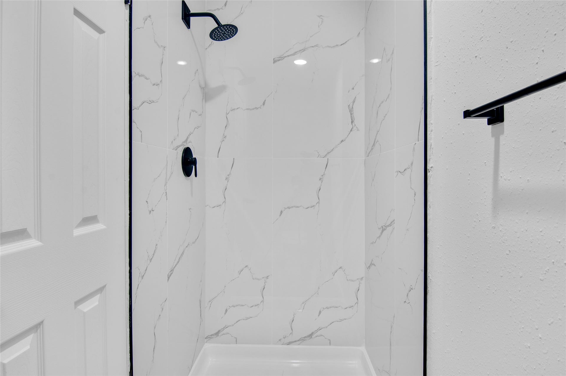 2916 Windchase Blvd, Houston, TX 77082 Elegant shower featuring sleek marble-style tiles and a modern black showerhead for a luxurious touch.