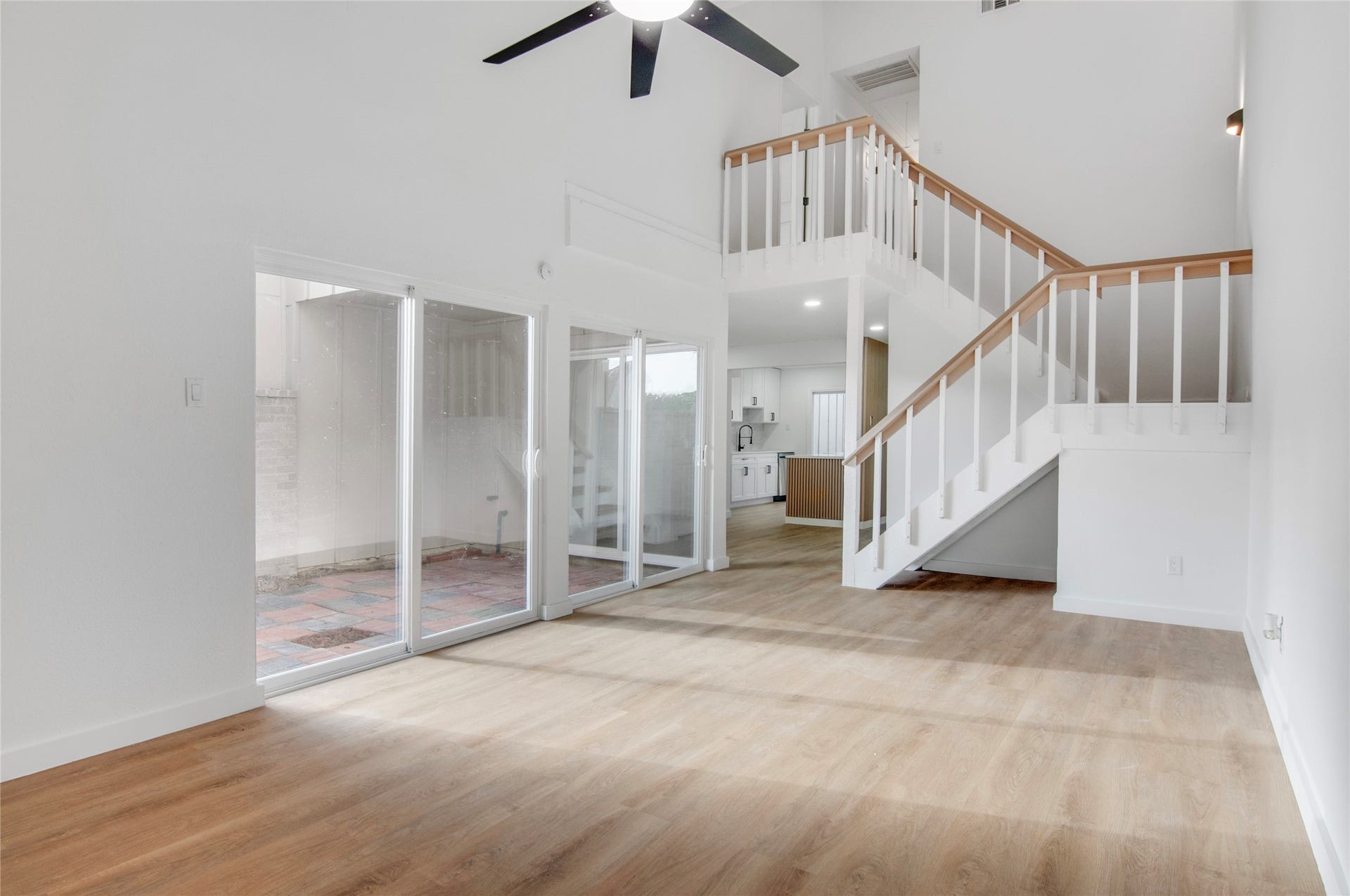 2916 Windchase Blvd, Houston, TX 77082 Spacious living area with high ceilings, abundant natural light from large glass doors, and an elegant staircase leading to the upper level.