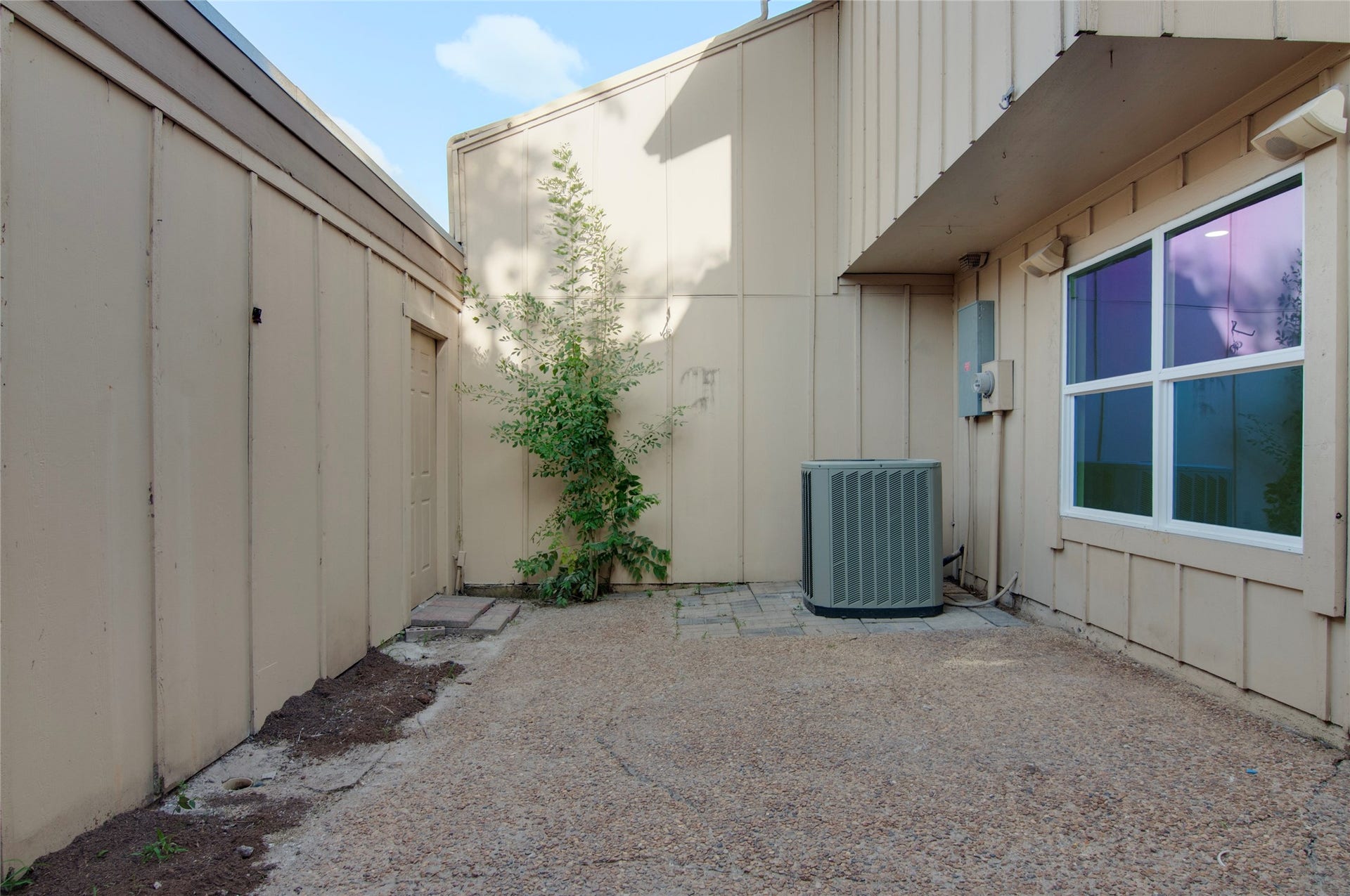 2916 Windchase Blvd, Houston, TX 77082 A private outdoor space with a clean pebble-finished patio, ideal for storage or a small garden area, featuring a convenient exterior utility unit.