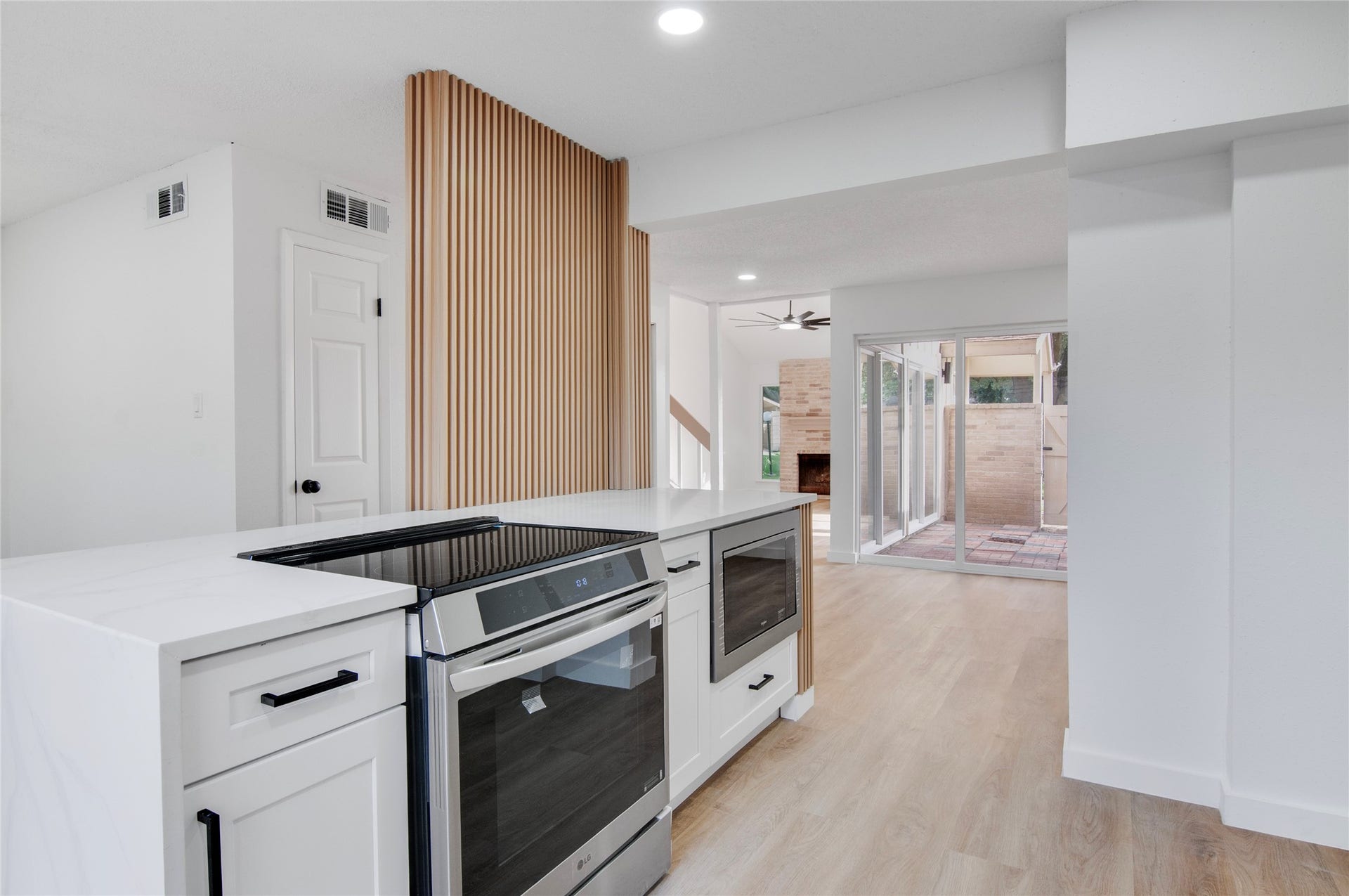 2916 Windchase Blvd, Houston, TX 77082 Modern kitchen with sleek appliances and a stylish island, seamlessly flowing into a bright living area with sliding glass doors leading to a cozy patio.