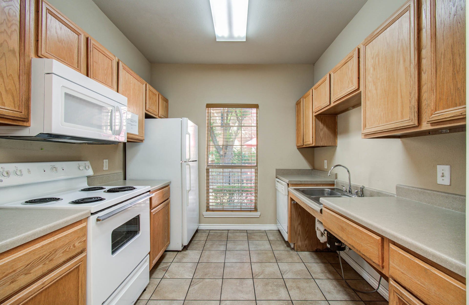 Clubhouse kitchen is fully equipped for entertaining with wooden cabinetry, essential appliances: stove, microwave, refrigerator, and dishwasher.
