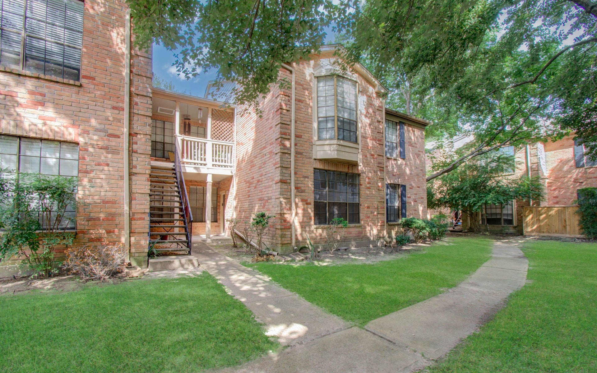 Braeswood Park Condo features brick buildings with lush green landscaping