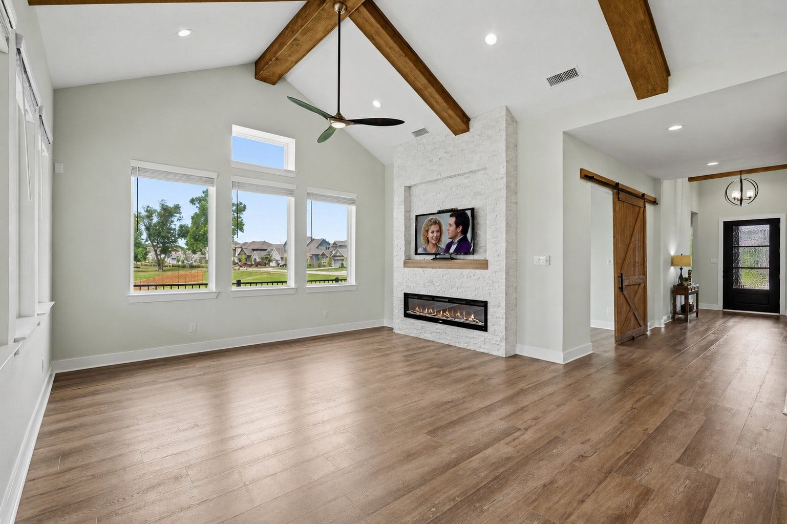 Drama is created by the soaring cathedral ceiling that draws the eye upward to the rough sawn wood beamed ceiling. Warmth is created by the floor-to-ceiling stacked stone wall. And, entertaining is created by the custom electronic fireplace with a 60 inset TV niche above the custom mantle.