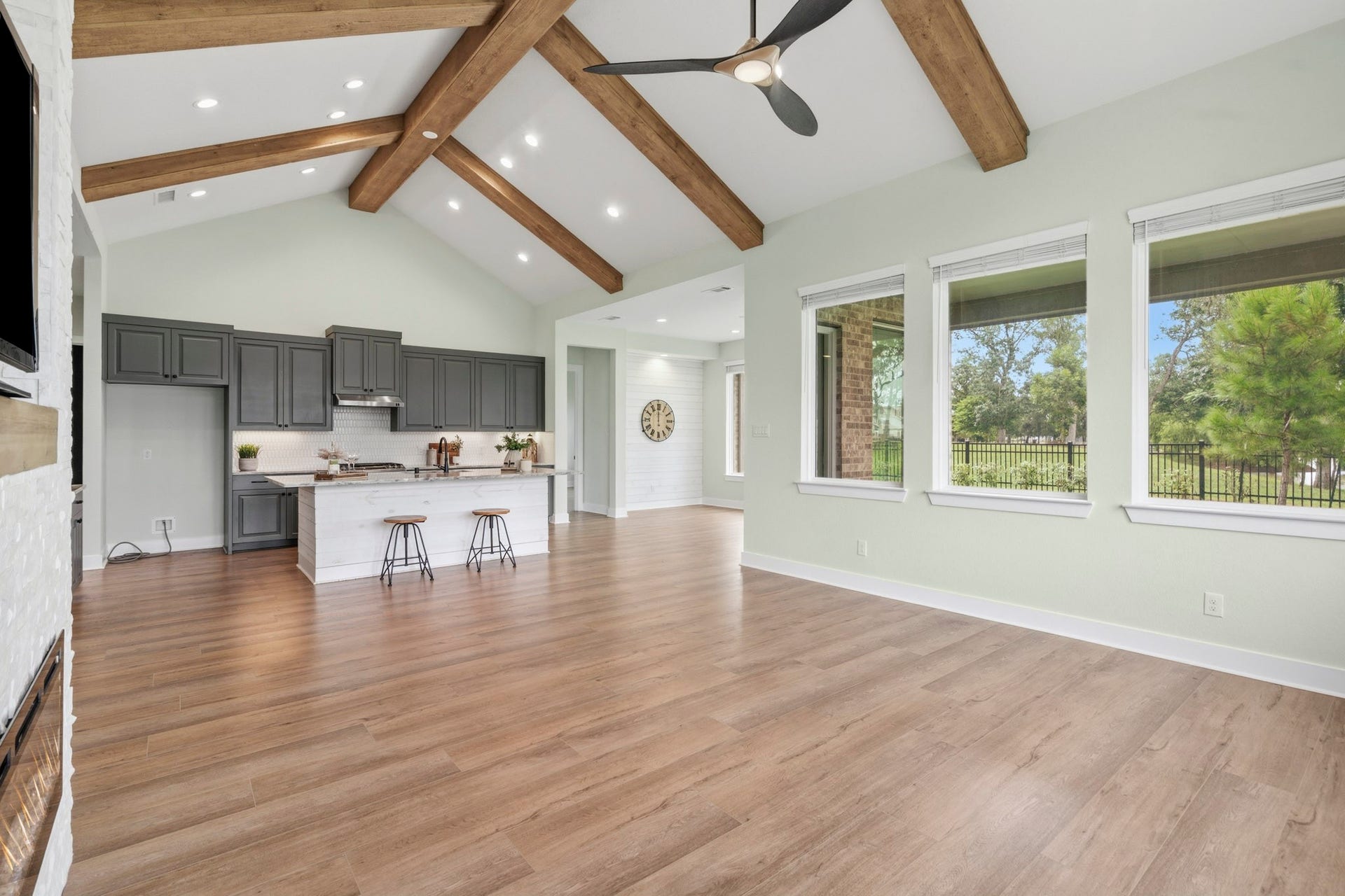 This view captures the grandeur of the space and shows how gracefully the Family Room flows to the Kitchen and how the walls of glass extend along the back of the entire home, flooding the space with natural light and breathtaking views.