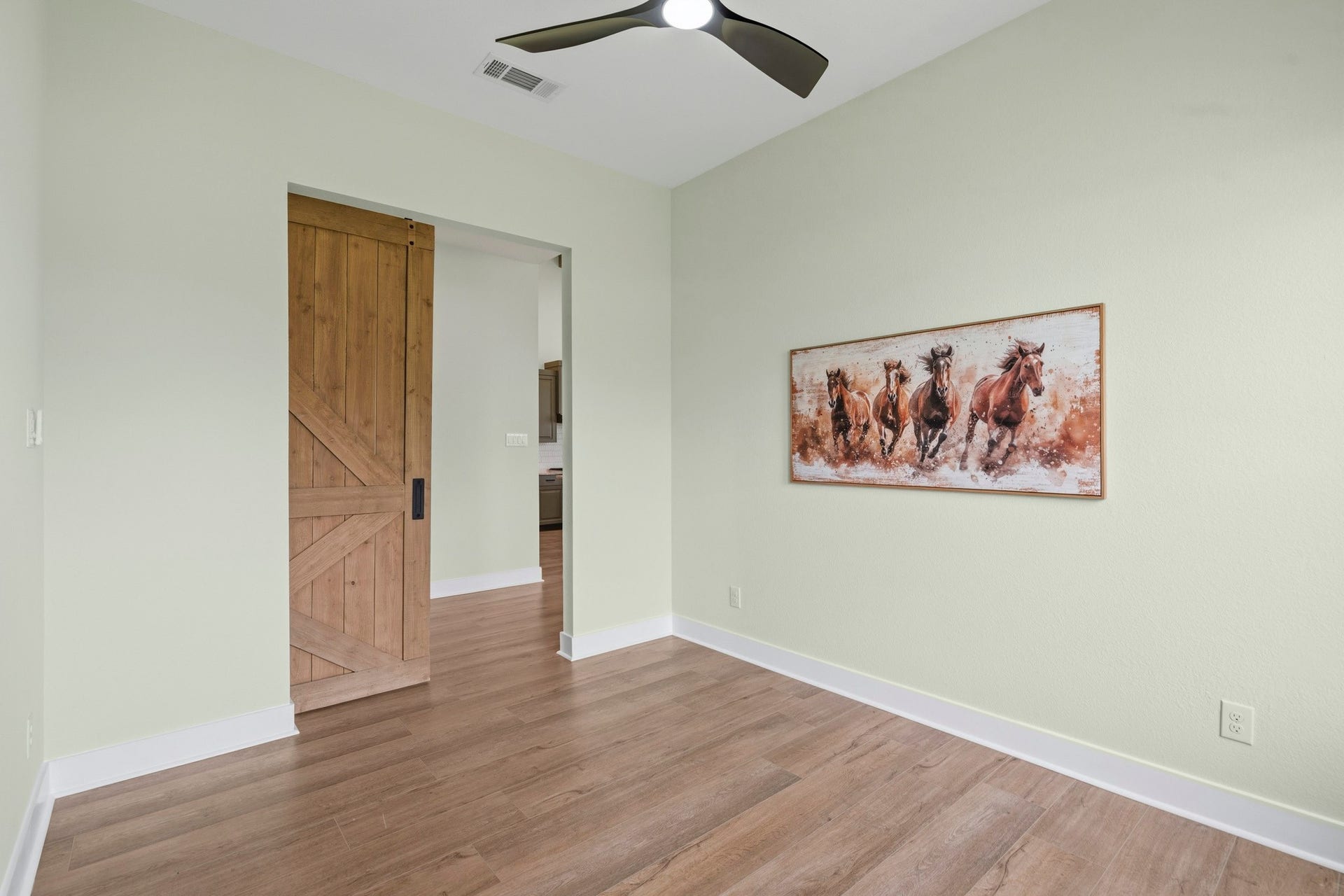 The Study, located directly off the Foyer, is accessible through the rustic, yet stately barn door. Overhead, an upgraded 60-inch fan is an artful mix of black and champagne gold serving both as a stylish focal point and a functional enhancement, ensuring the room remains comfortably illuminated and well-circulated year-round.