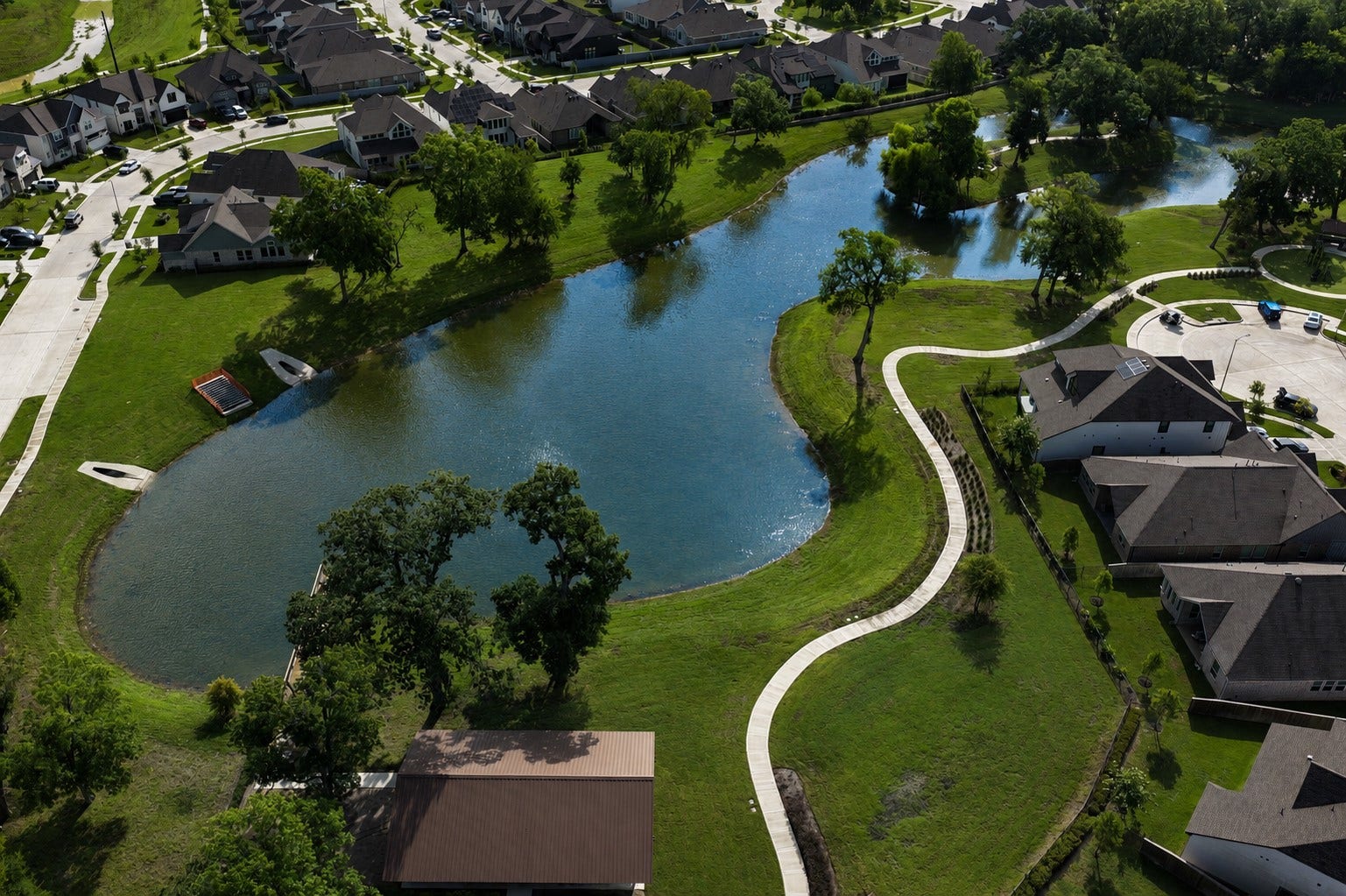 This birds-eye view highlights this community's most striking scenic lake and most photographed amenity. It is enveloped with gorgeous trees and thoughtfully appointed with walking trails, a pier, an architectural designed bridge, a childrens park and a huge, covered Entertainment Center.