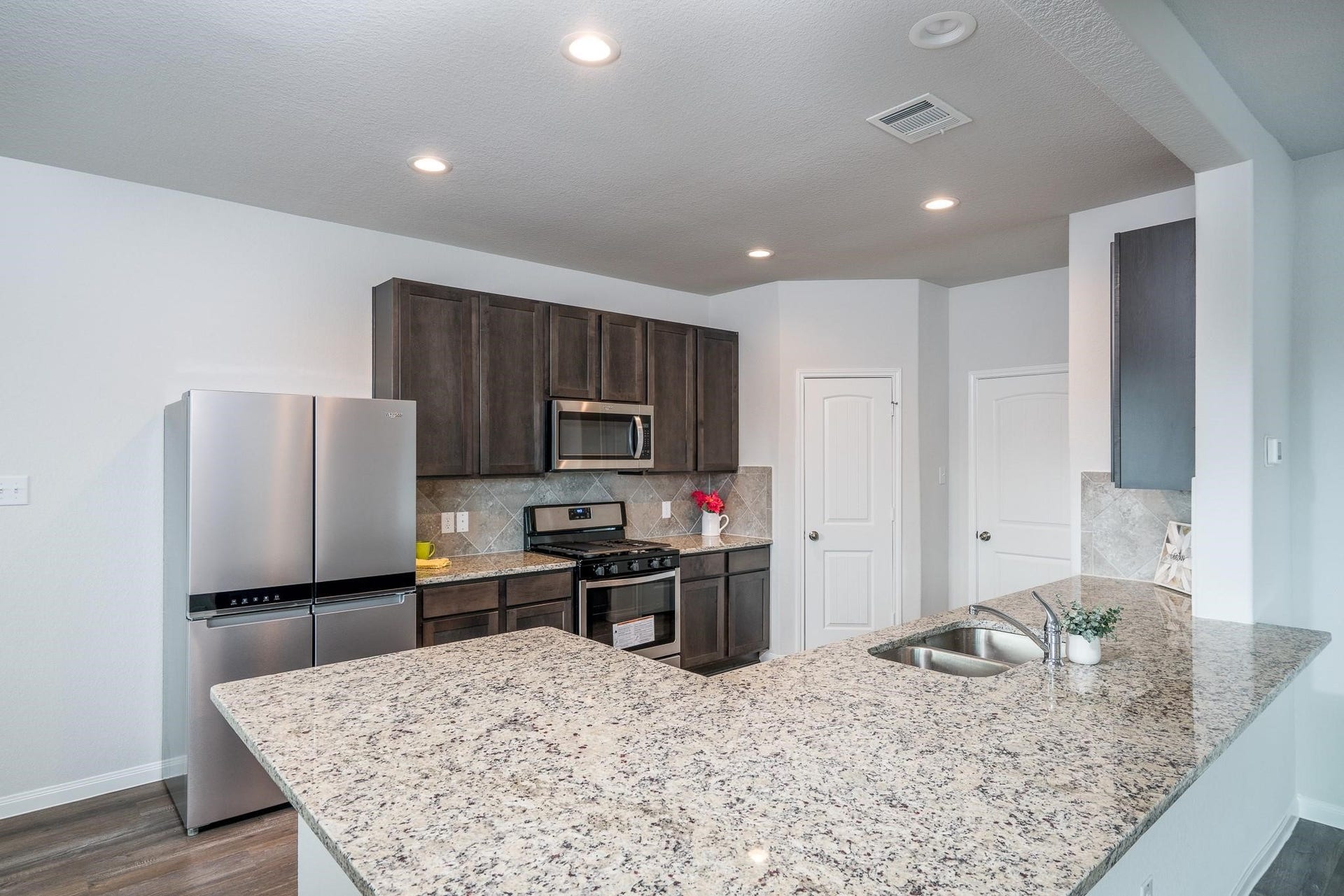 2910 Orchid Ranch Drive, Katy, TX 77494 Modern kitchen with sleek stainless steel appliances, elegant granite countertops, and rich dark cabinetry, offering ample storage and a stylish backsplash.