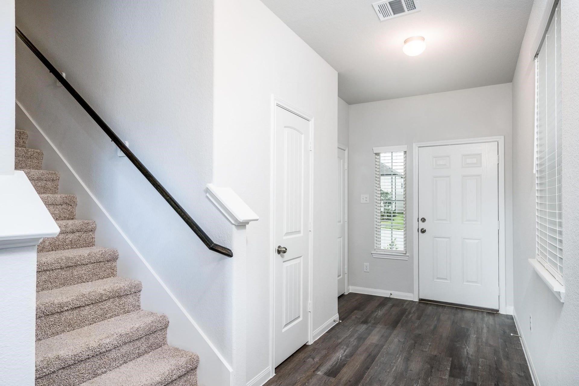 2910 Orchid Ranch Drive, Katy, TX 77494 Inviting entryway with sleek wood flooring and a carpeted staircase, offering a warm and welcoming first impression.