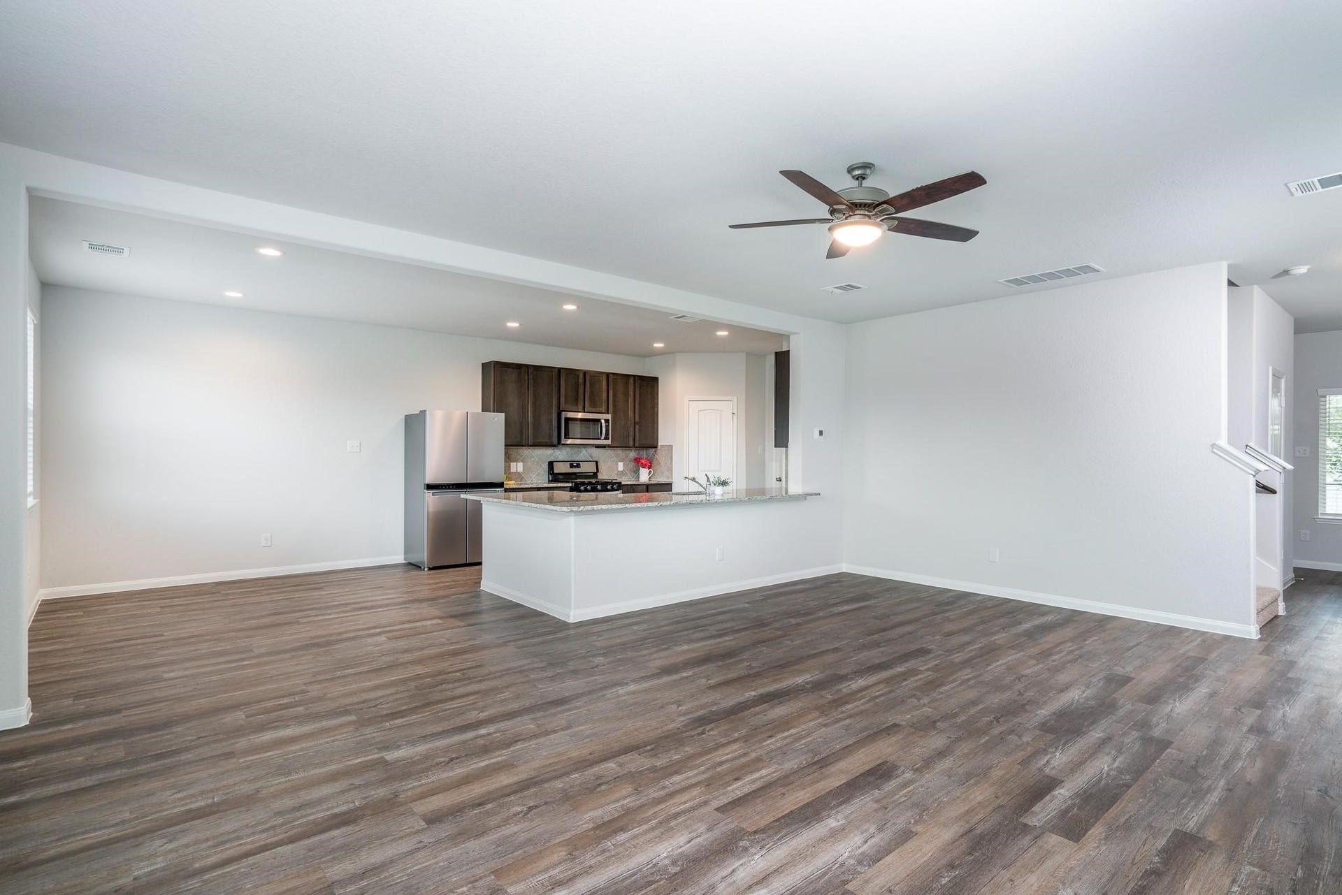 2910 Orchid Ranch Drive, Katy, TX 77494 Open-concept living area with elegant hardwood flooring and a modern kitchen featuring stainless steel appliances and a spacious island.