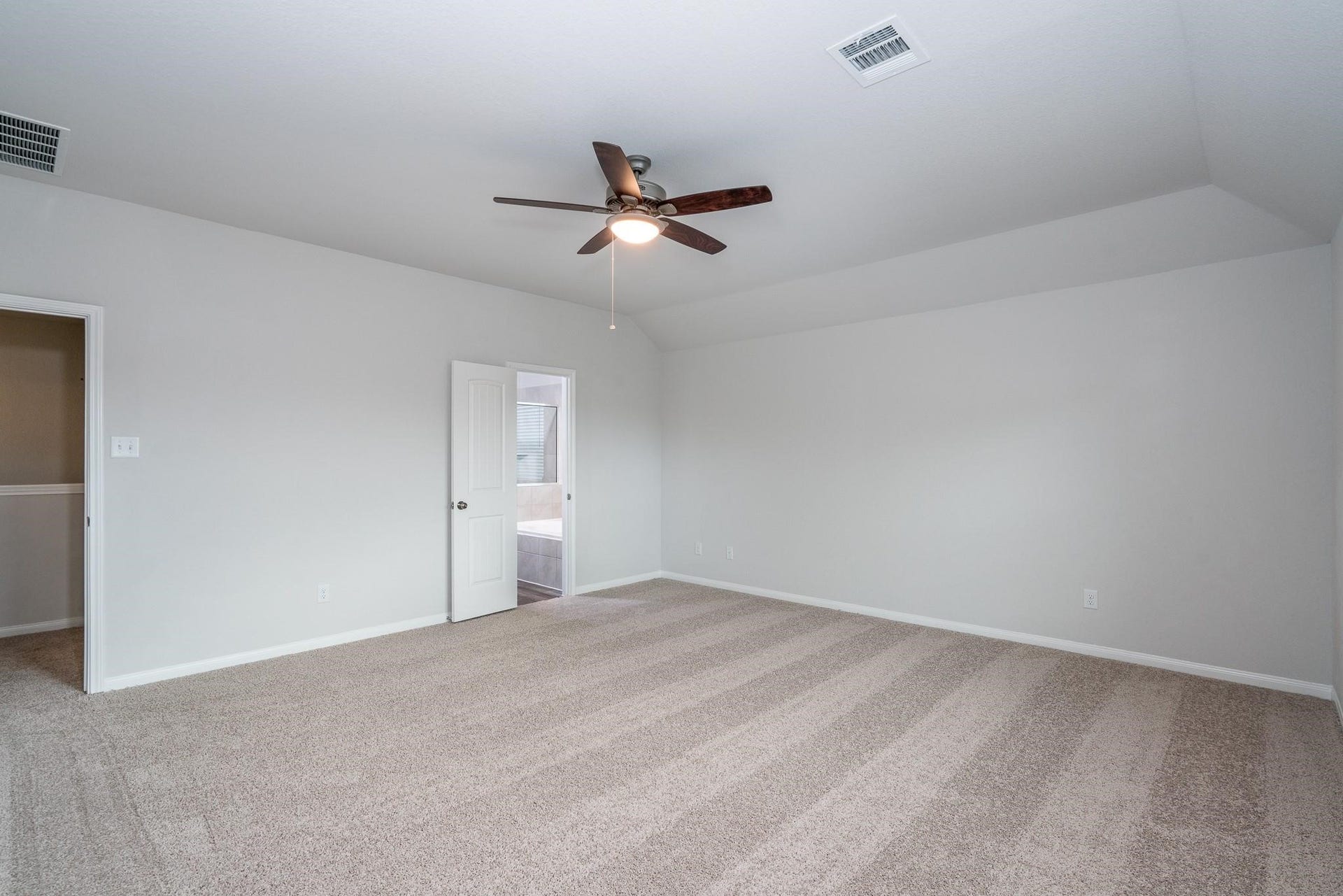 2910 Orchid Ranch Drive, Katy, TX 77494 Spacious bedroom featuring plush carpeting, neutral walls, and a ceiling fan, with an en-suite bathroom for added convenience.