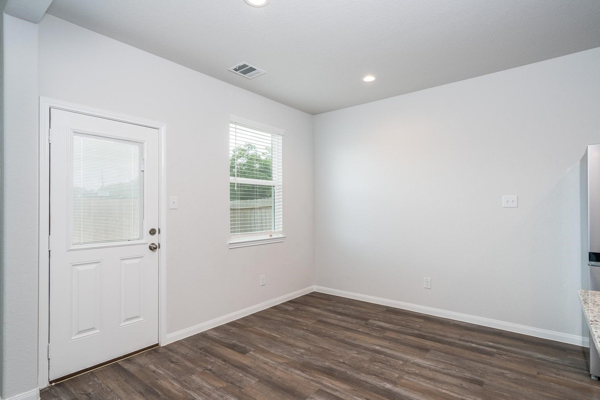 2910 Orchid Ranch Drive, Katy, TX 77494 Bright and inviting space with sleek wood flooring, a large window for natural light, and a convenient side door, perfect for easy access and functionality.