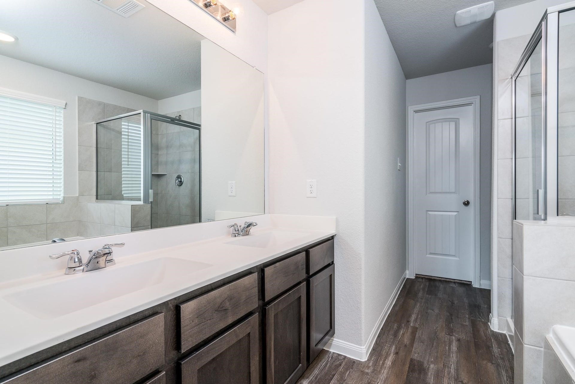 2910 Orchid Ranch Drive, Katy, TX 77494 Modern bathroom featuring a dual-sink vanity, elegant dark wood cabinetry, and a sleek glass-enclosed shower.