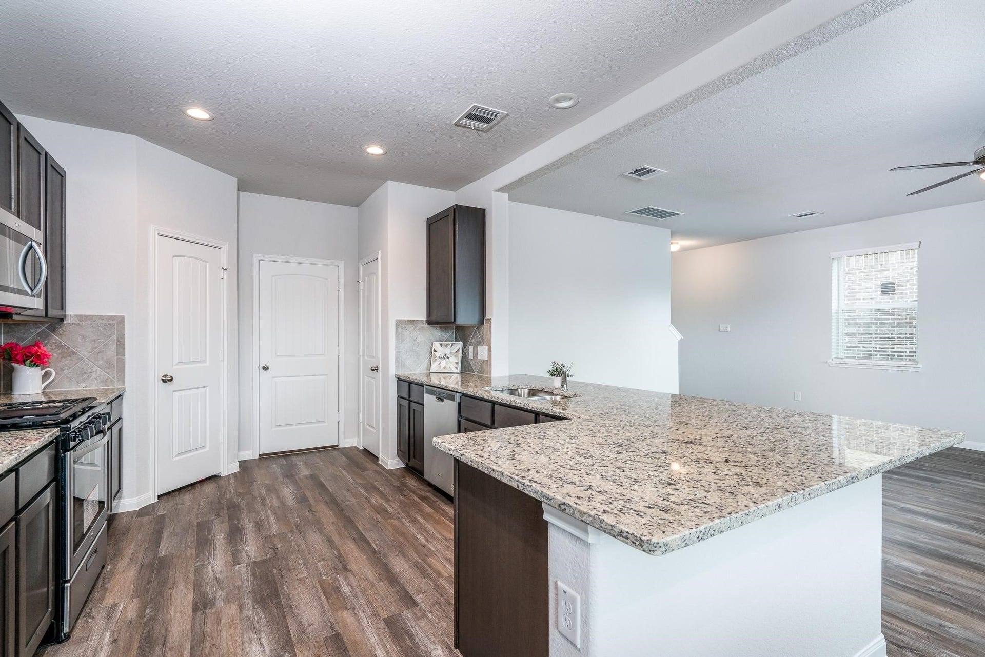 2910 Orchid Ranch Drive, Katy, TX 77494 Spacious kitchen with sleek granite countertops, modern stainless steel appliances, and rich wood cabinetry, seamlessly flowing into an open living area.