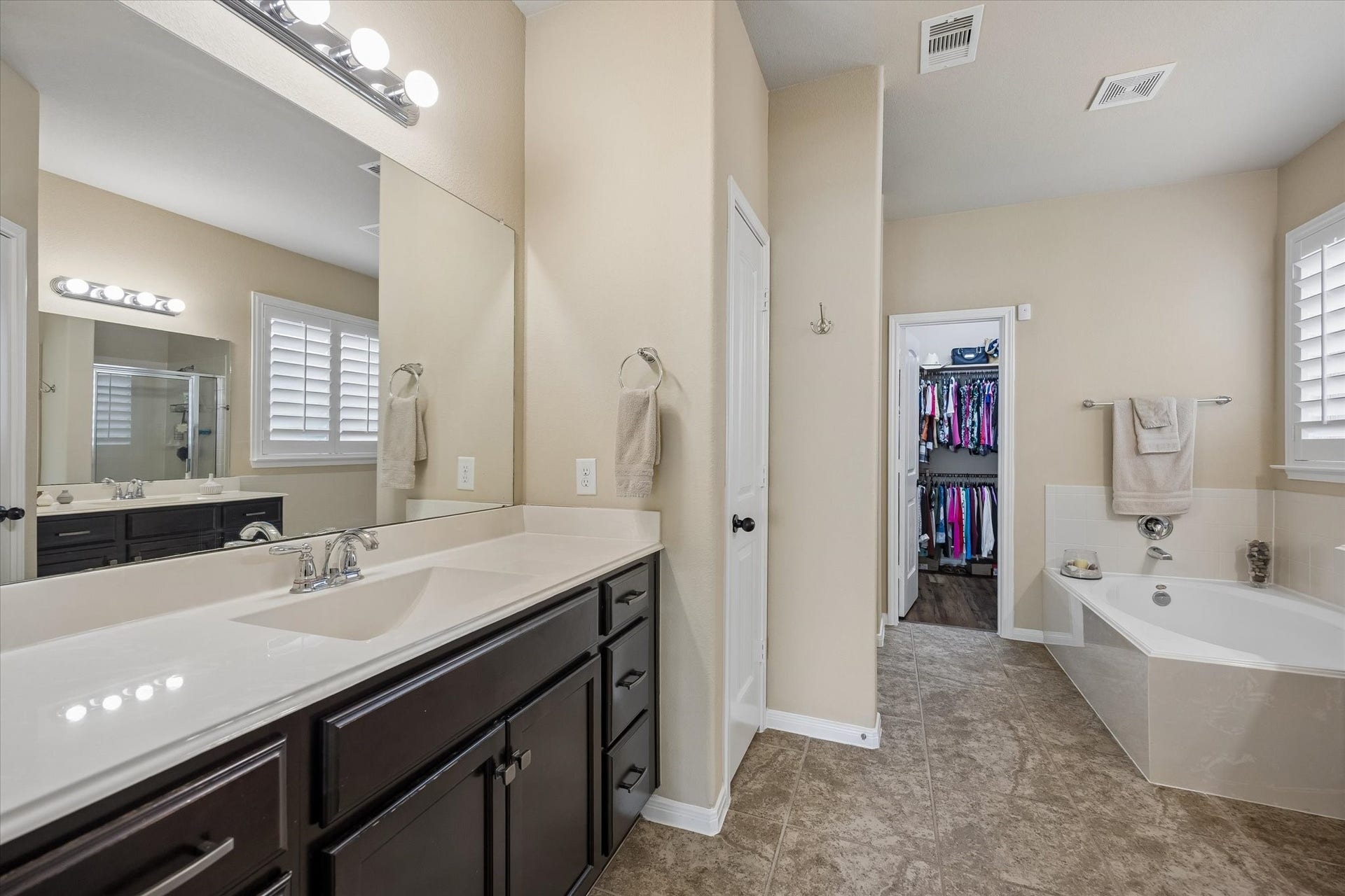 Primary bath with dual vanities, soaking tub, separate shower, and walk-in-closet
