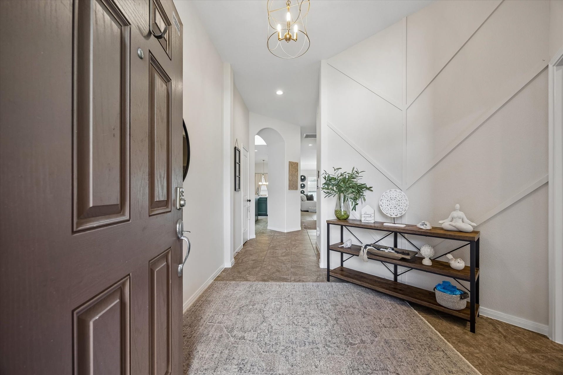 Wide entry hallway with arched openings and open view into home with accent wall