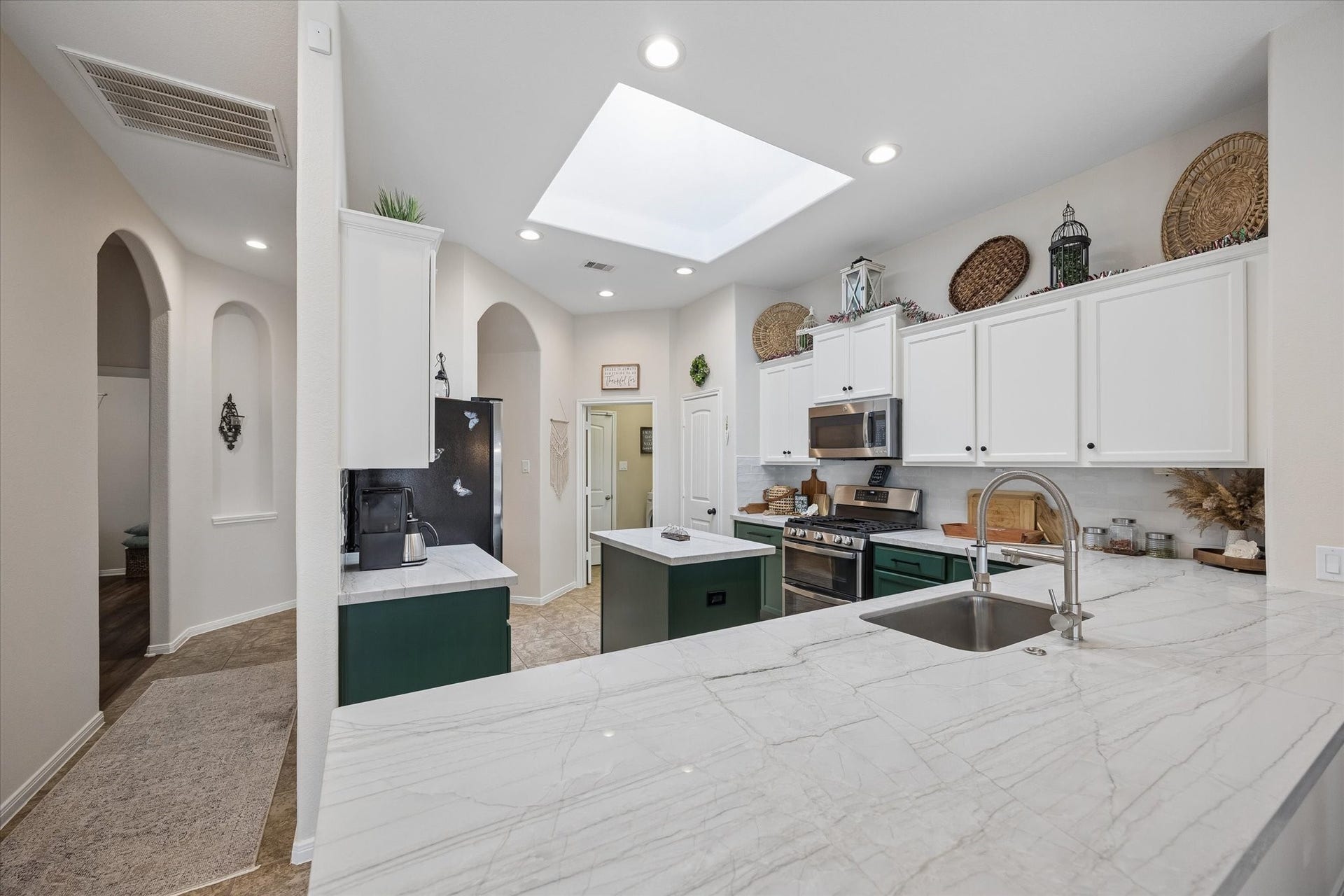 Updated kitchen featuring quartzite countertops, a center island, and skylight