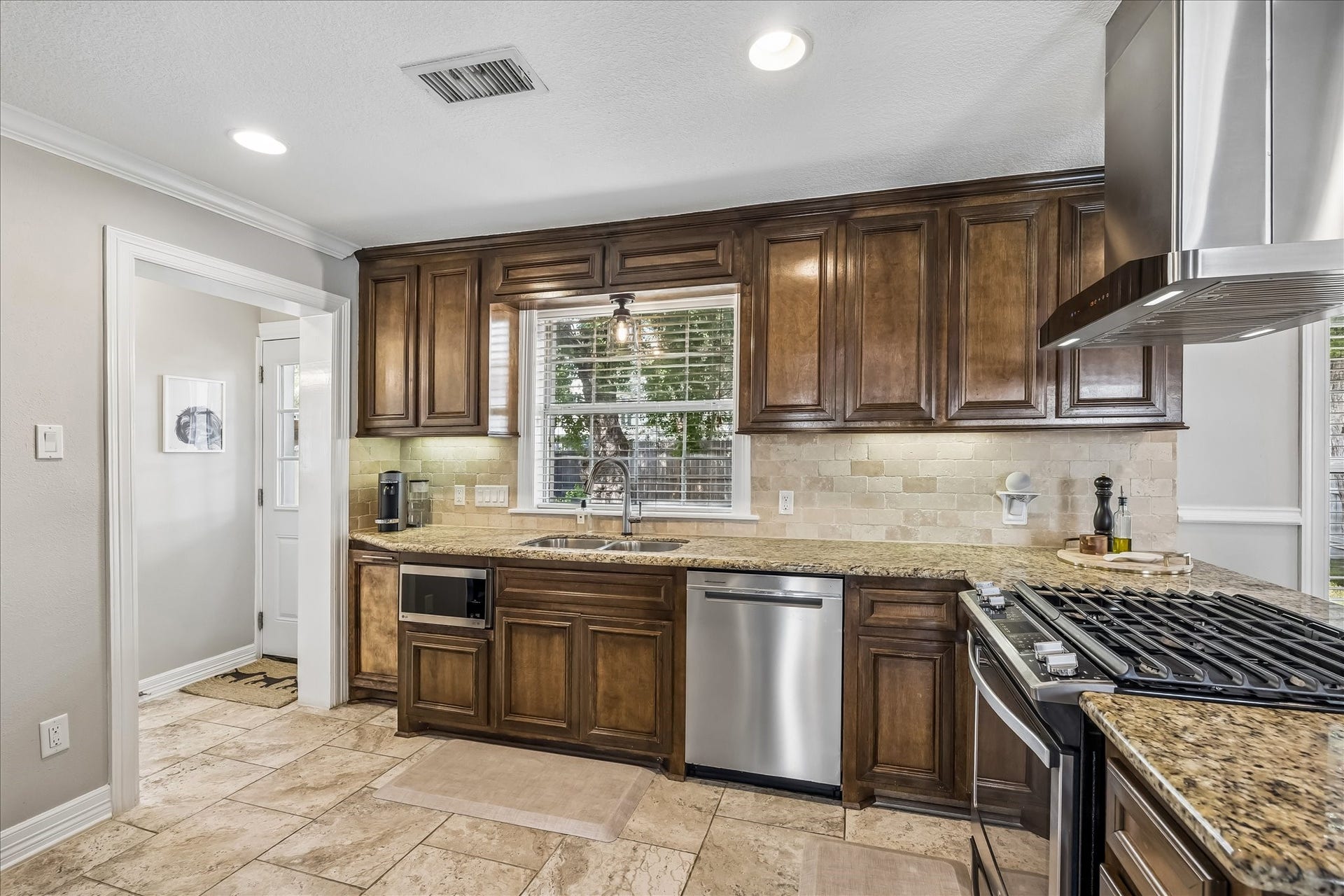1909 Rosewood Street, Houston, TX 77004 Another angle shows the kitchens generous cabinet run, granite work surfaces, dishwasher, and sink positioned beneath the window.