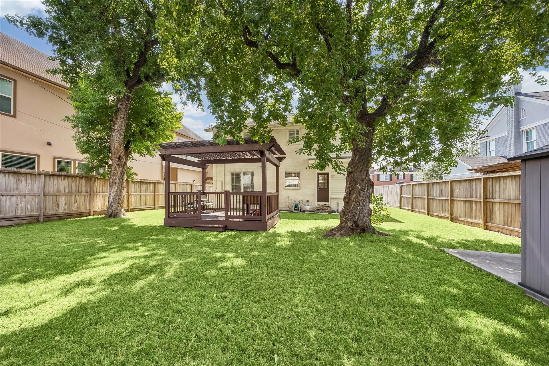 1909 Rosewood Street, Houston, TX 77004 Mature shade trees create a peaceful backdrop across the fenced yard, with the pergola positioned toward the rear for added separation.