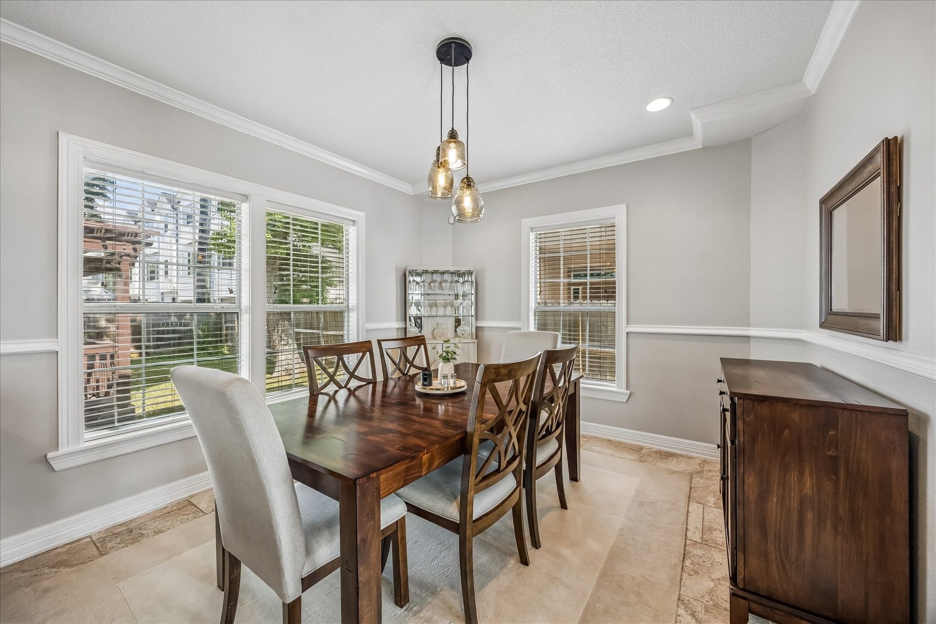1909 Rosewood Street, Houston, TX 77004 Dining area sits between large windows with chair-rail detailing, warm wood furniture, and a statement pendant overhead.