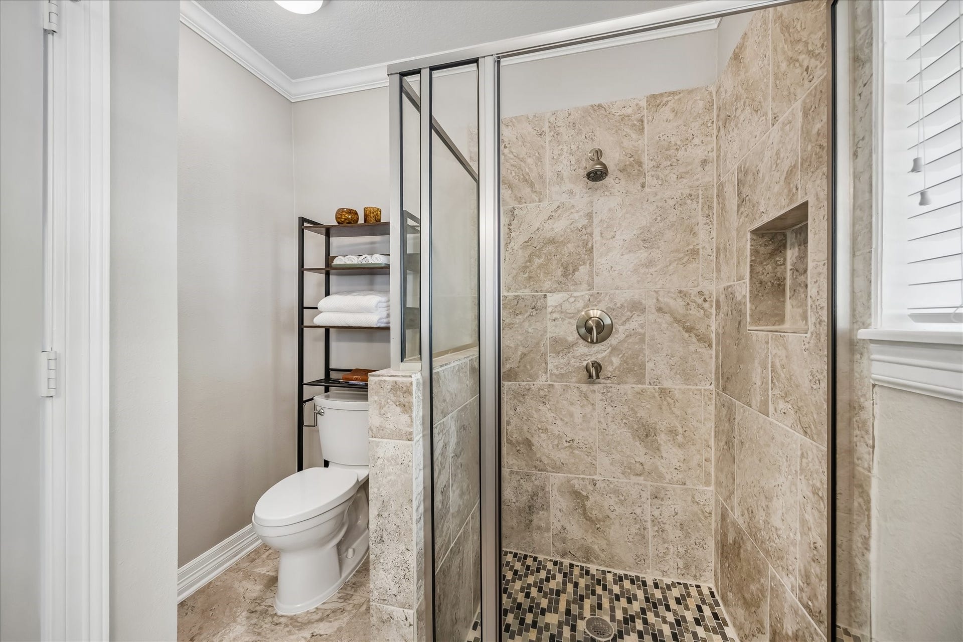 1909 Rosewood Street, Houston, TX 77004 Stone tile wraps the shower from floor to ceiling, complemented by a built-in niche and pebble-style floor detailing.