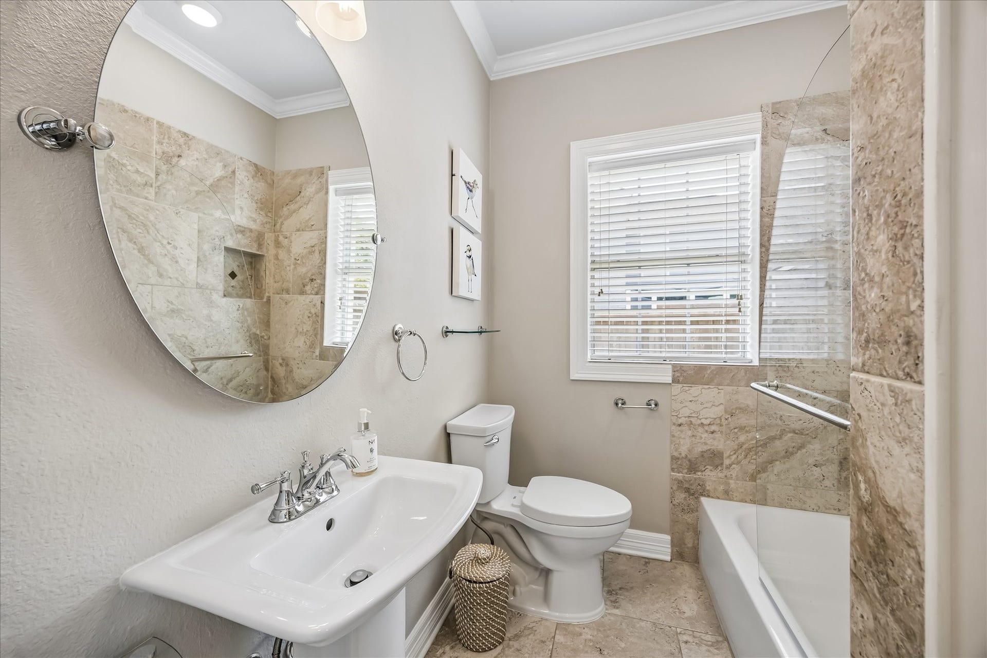 1909 Rosewood Street, Houston, TX 77004 Full bath on the first floor offers a tub-shower combination, pedestal sink, large round mirror, and natural light.