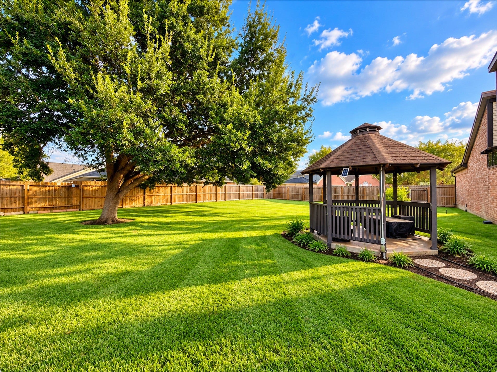 3902 Crystal Falls Drive, Missouri City, TX 77459 Spacious backyard showcasing a mature shade tree, manicured lawn, covered gazebo, landscaped garden beds, and a charming stepping-stone walkway.
*Virtually enhanced photo