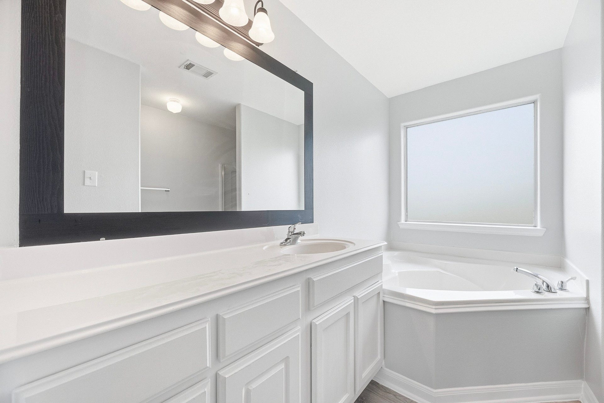28838 Frio River Loop, Spring, TX 77386 Primary bathroom features an extended vanity, framed mirror, and corner tub beneath a privacy window.