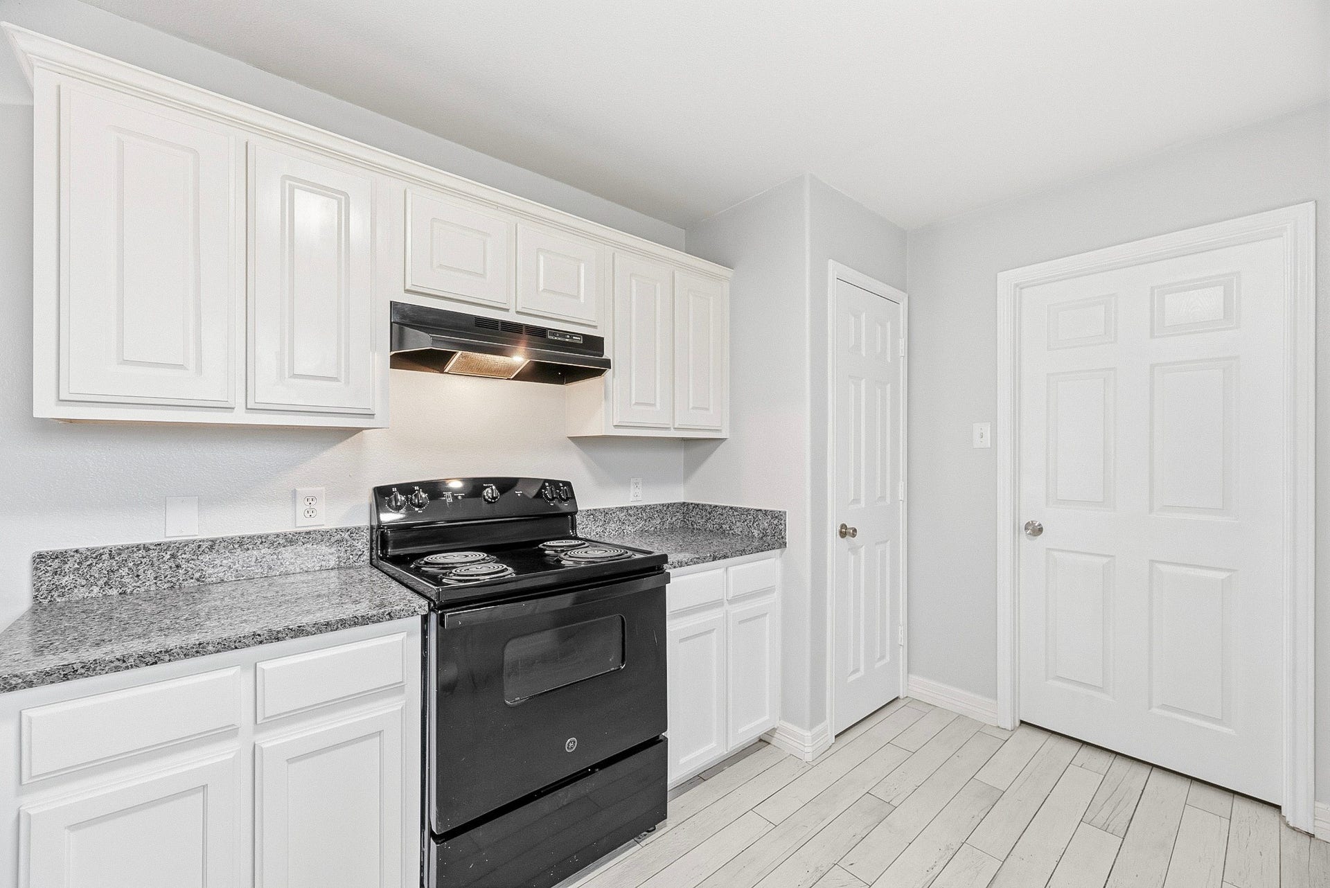 28838 Frio River Loop, Spring, TX 77386 Black electric range and matching hood contrast with white cabinetry and patterned counters.
