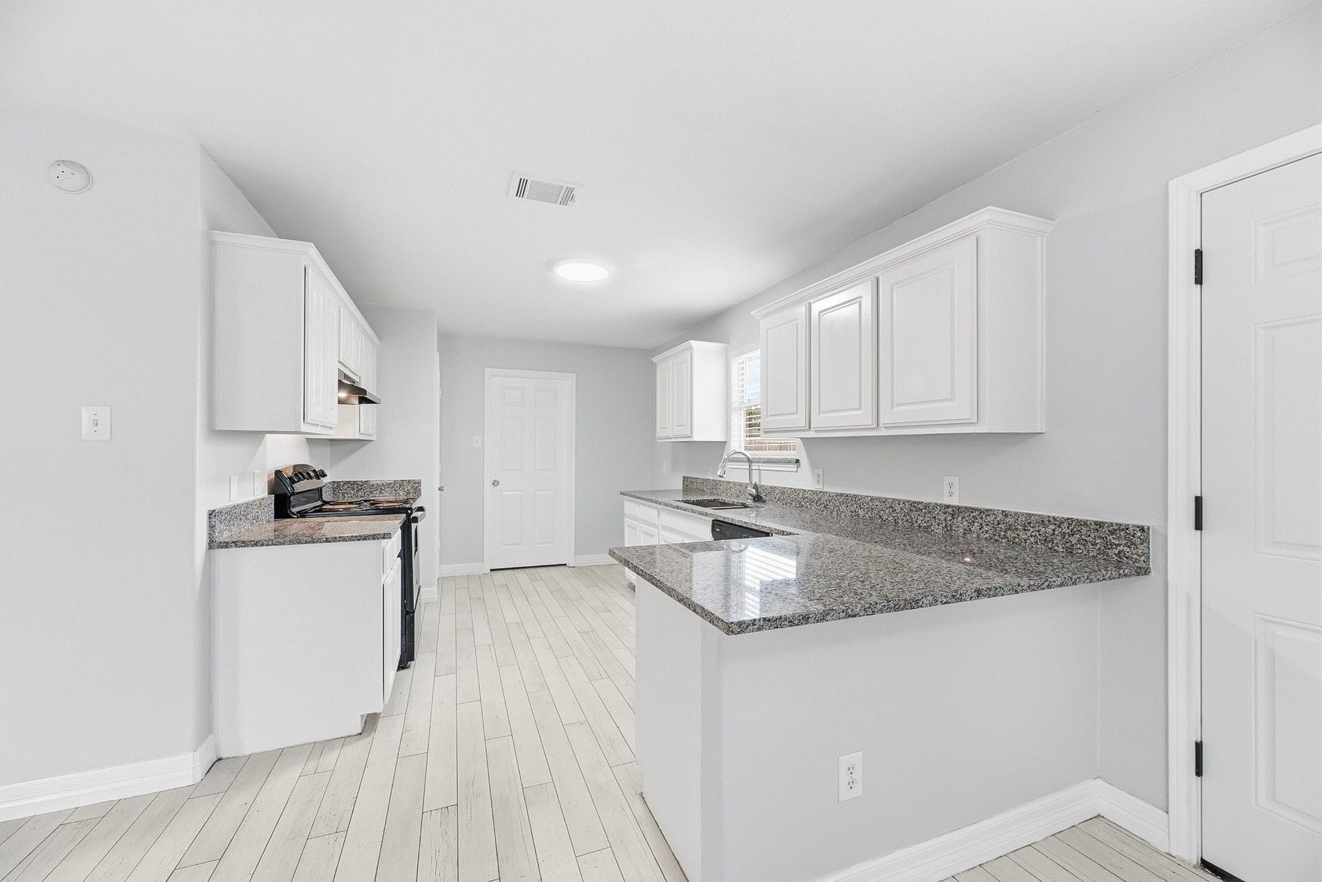 28838 Frio River Loop, Spring, TX 77386 White raised-panel cabinetry and patterned countertops frame the kitchens peninsula and black appliances.