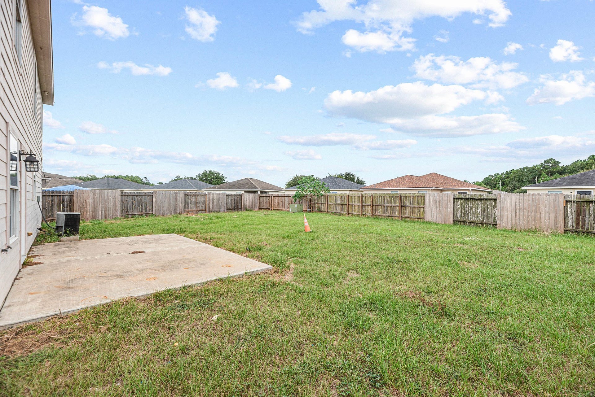 28838 Frio River Loop, Spring, TX 77386 Original backyard lawn condition shown with the existing concrete patio, wood fence, and utility equipment.