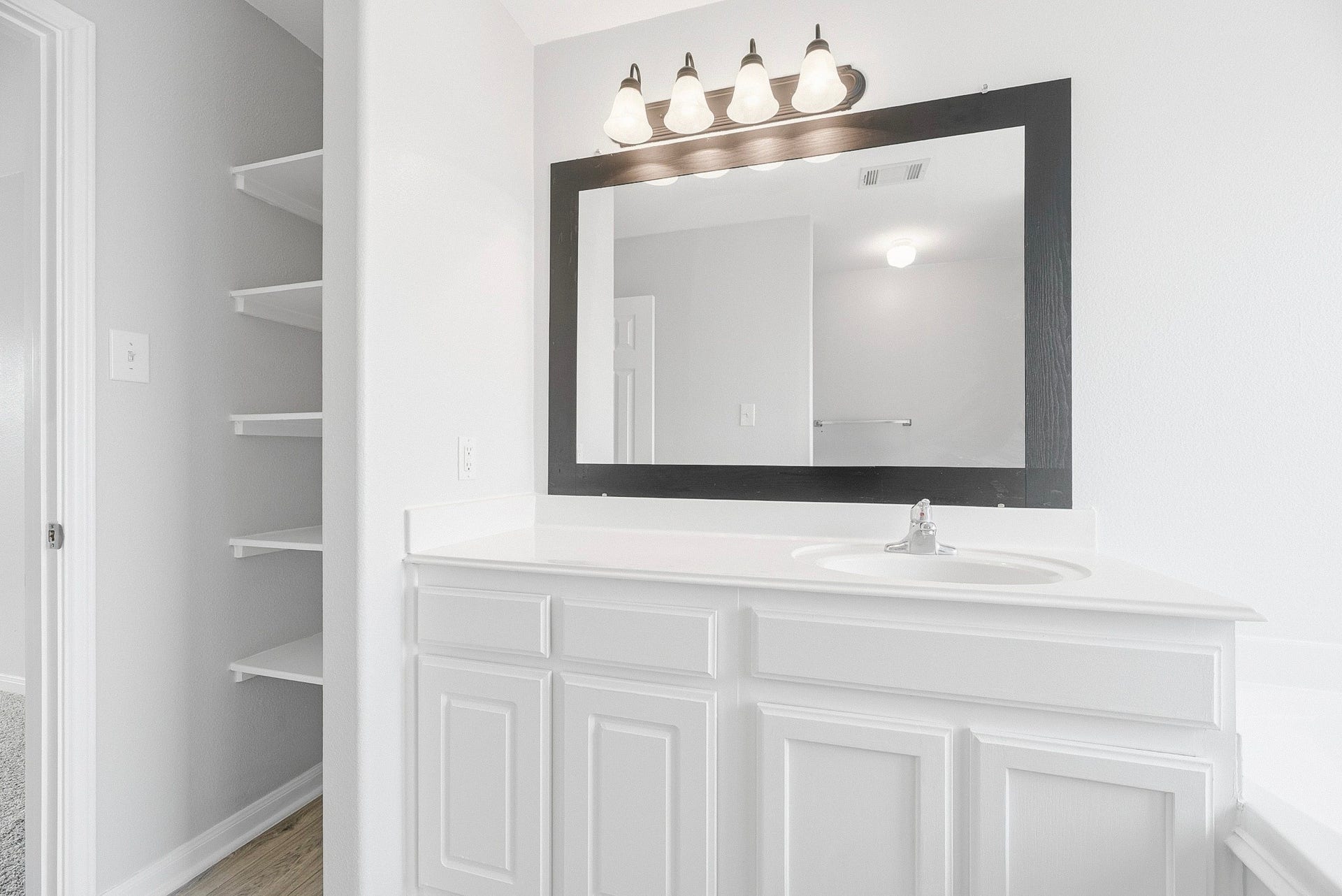 28838 Frio River Loop, Spring, TX 77386 An extended vanity counter pairs with white cabinetry, a framed mirror, and open linen shelving.