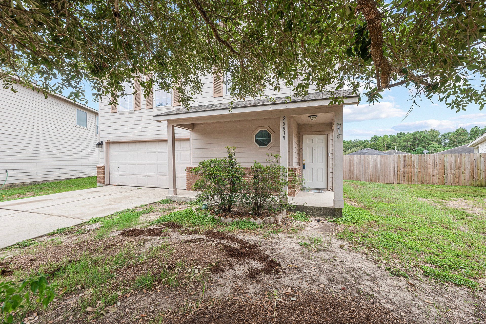 28838 Frio River Loop, Spring, TX 77386 Original lawn condition shown beside the covered porch, attached garage, and mature shade tree.
