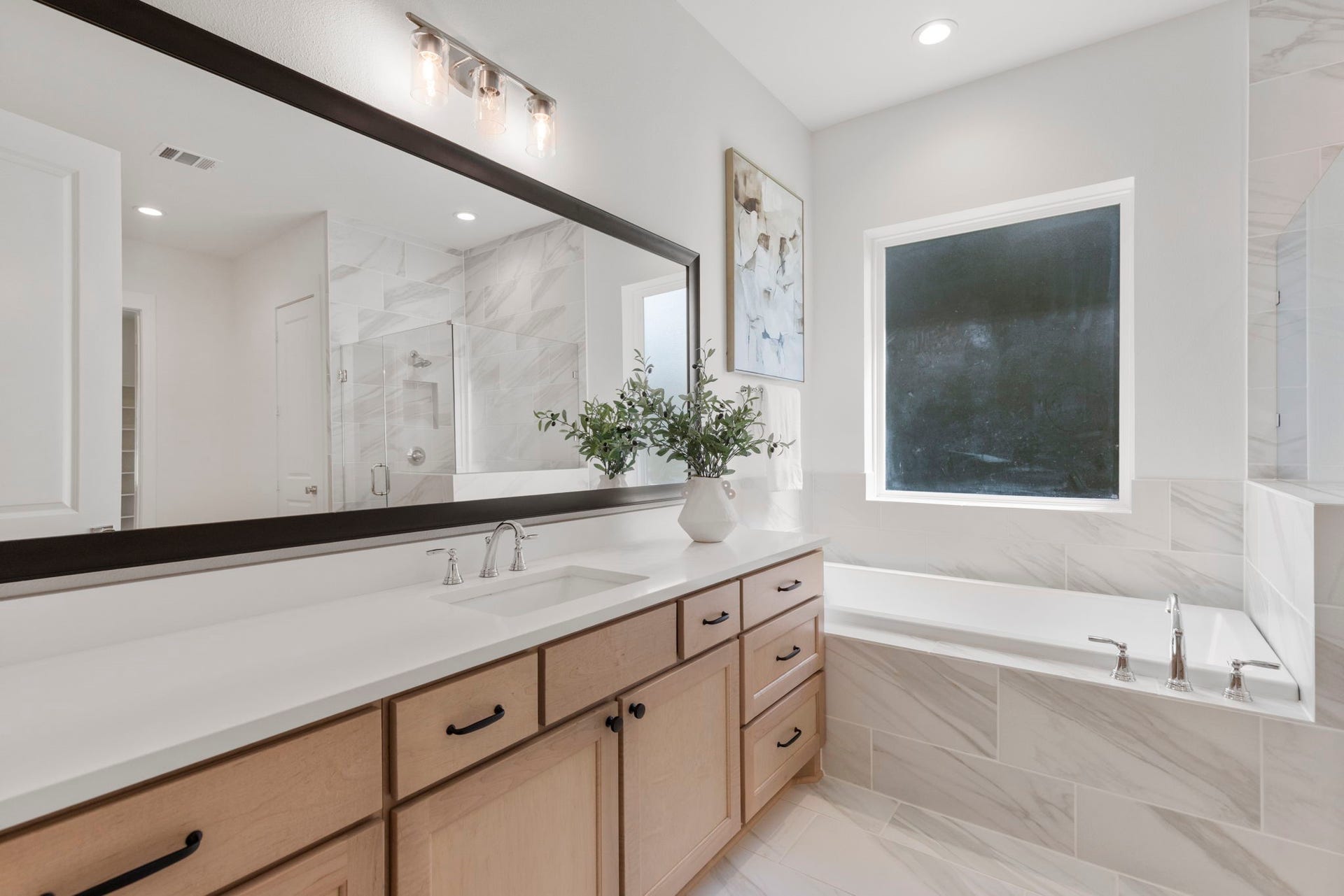 This modern soaking tub creates a spa-like retreat, perfectly positioned under a window to provide abundant natural light throughout.