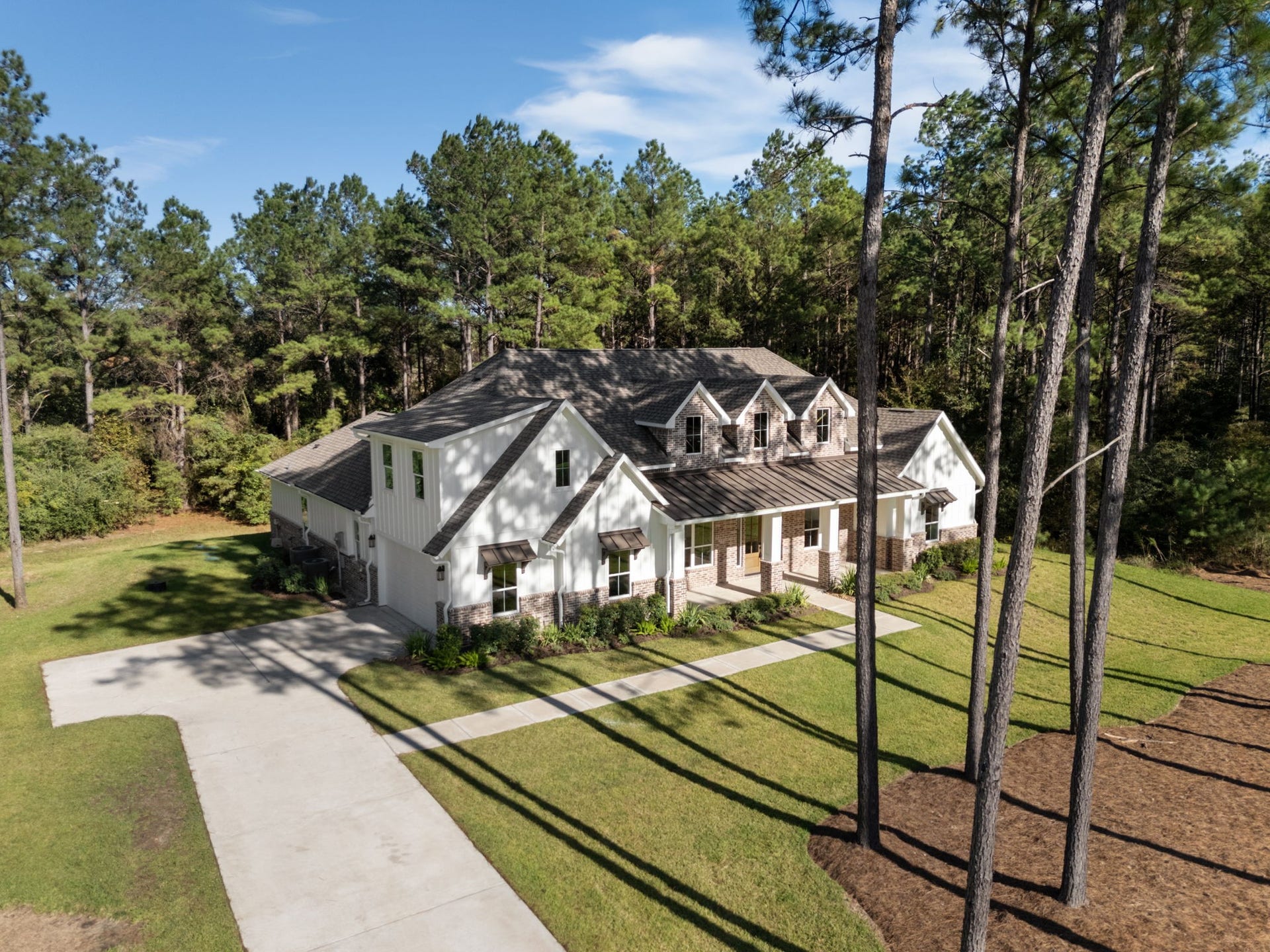 This elevated view highlights the home's impeccable architectural details, including charming dormer windows, a stylish metal roof over the front porch, and elegant window awnings.