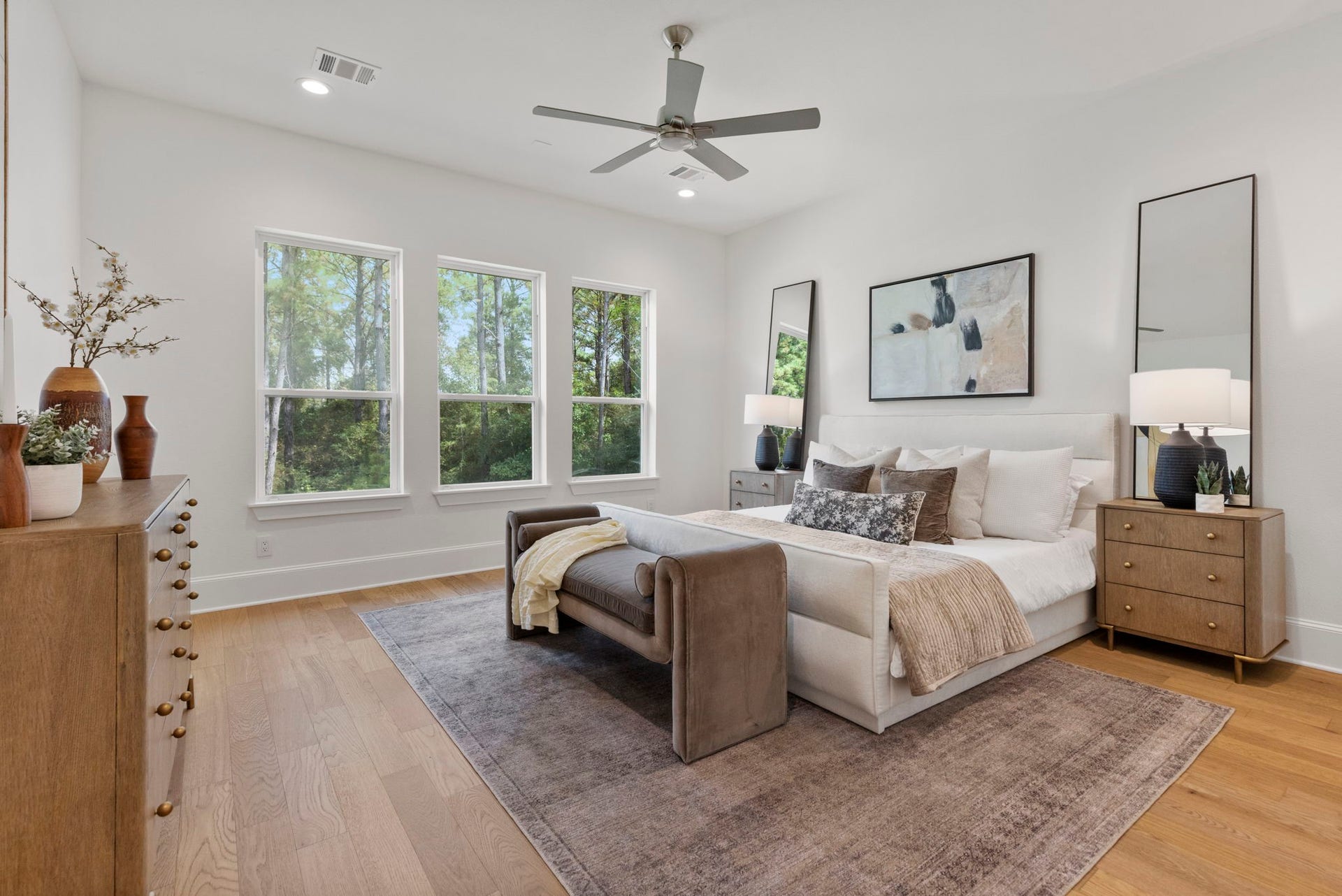 The primary suite features expansive windows that offer stunning views of the surrounding landscape, infusing the space with a serene, organic feel.