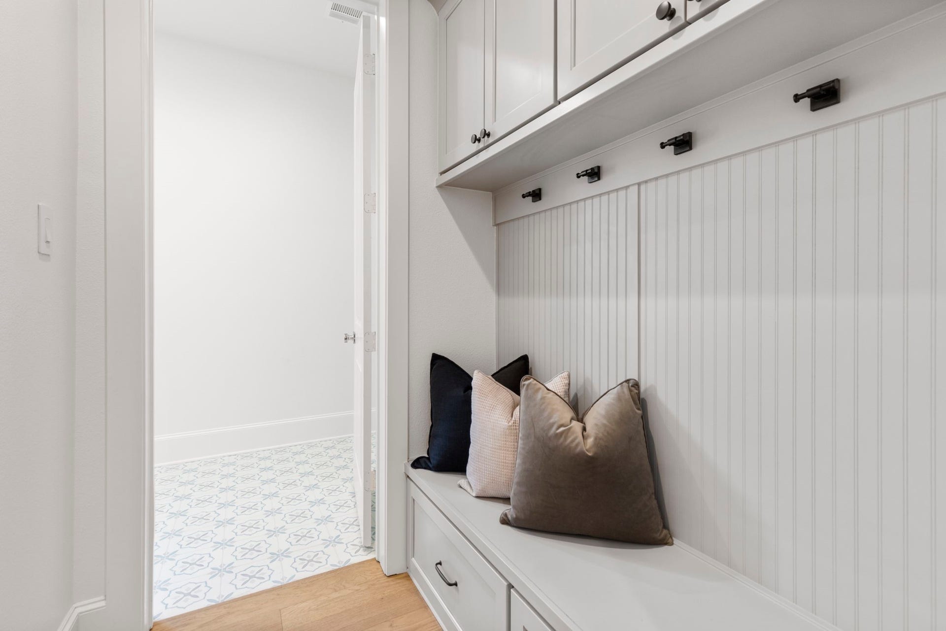 Custom mudroom drop zone featuring integrated bench seating with deep storage drawers for shoes and gear, complemented by overhead cabinetry for additional organization.