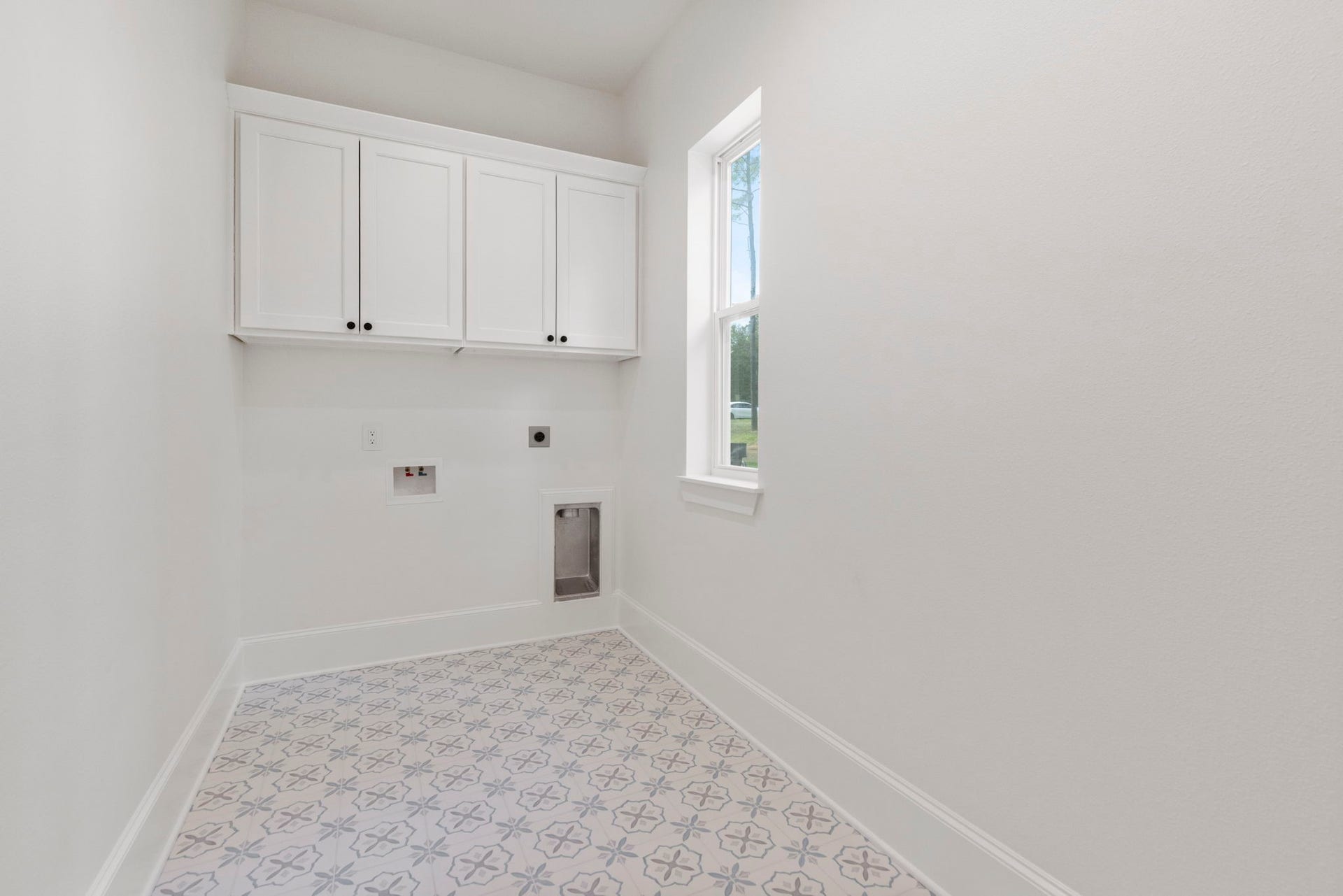 The laundry room has gorgeous tile floors, custom cabinets, and a window for views and natural lighting.