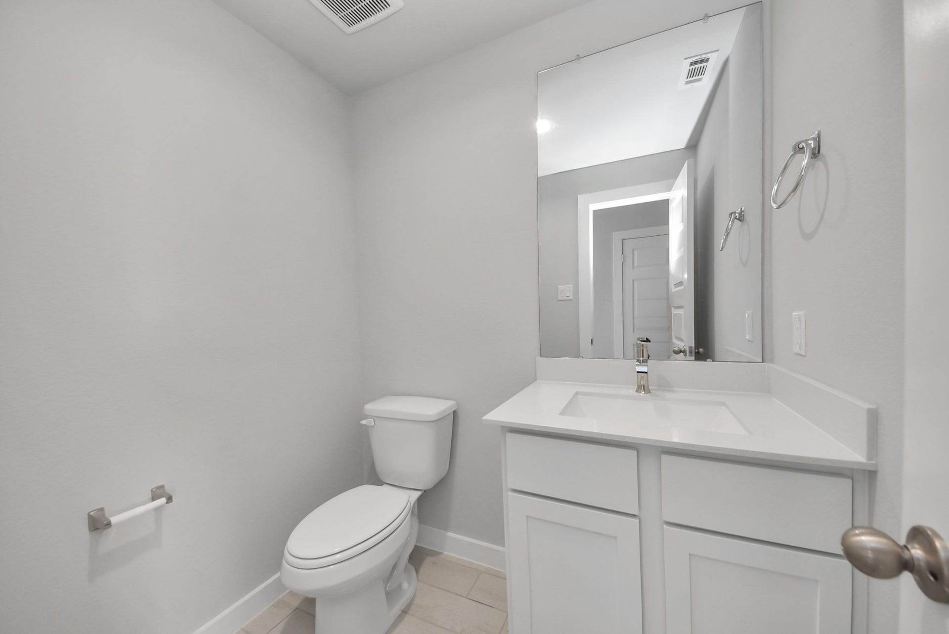 15111 Statice Trail, Houston, TX 77044 Sophisticated half bathroom adorned with contemporary finishes. The elegant 5-panel door welcomes you to a space where style meets functionality. Notice the sleek hardware accents that add a touch of modern charm. The vanity boasts light-colored countertops, beautifully complemented by a tasteful vanity light, creating a well-lit and inviting atmosphere.