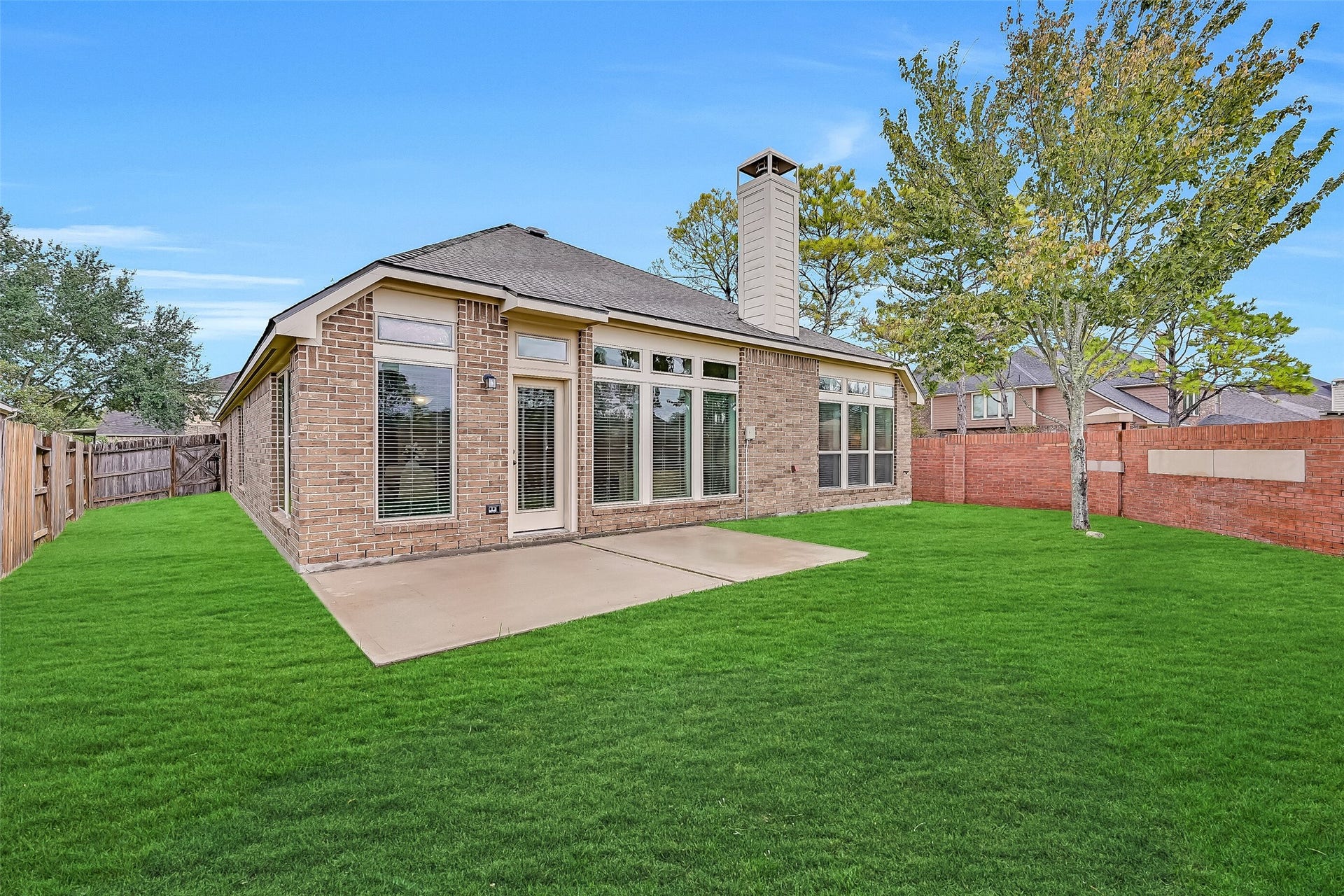 Enjoy outdoor relaxation in this generously sized backyard featuring a spacious concrete patio, lush green lawn & substantial brick privacy wall along the rear property line. The home's beautiful brick exterior & impressive collection of tall windows create an attractive backdrop for outdoor gatherings.