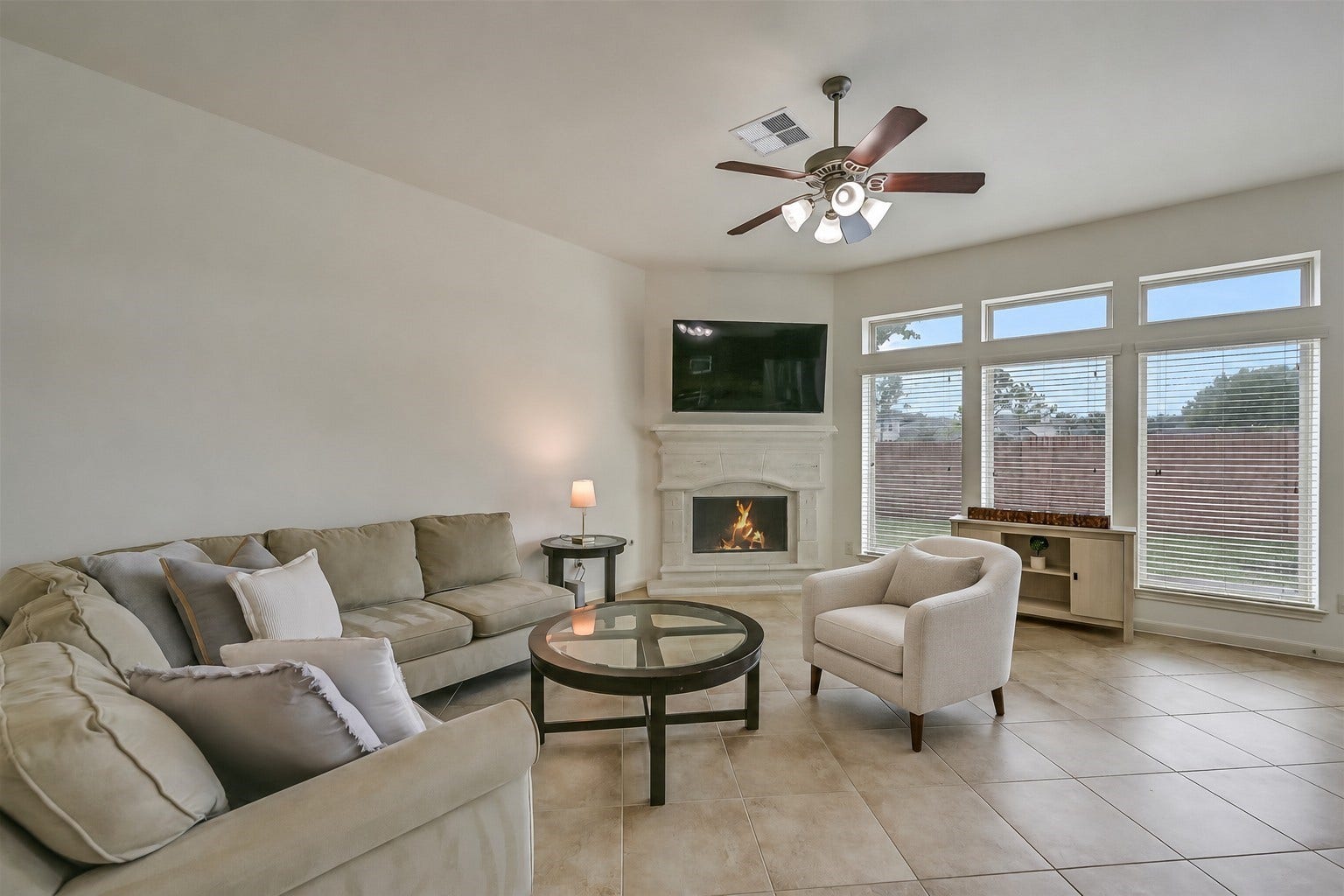 A beautiful cast-stone fireplace creates a striking focal point in the spacious family room! Tall windows with transoms above fill the space with natural light while overlooking the backyard. Neutral tile flooring, a ceiling fan & freshly painted walls provide a versatile backdrop for a variety of furnishings.
