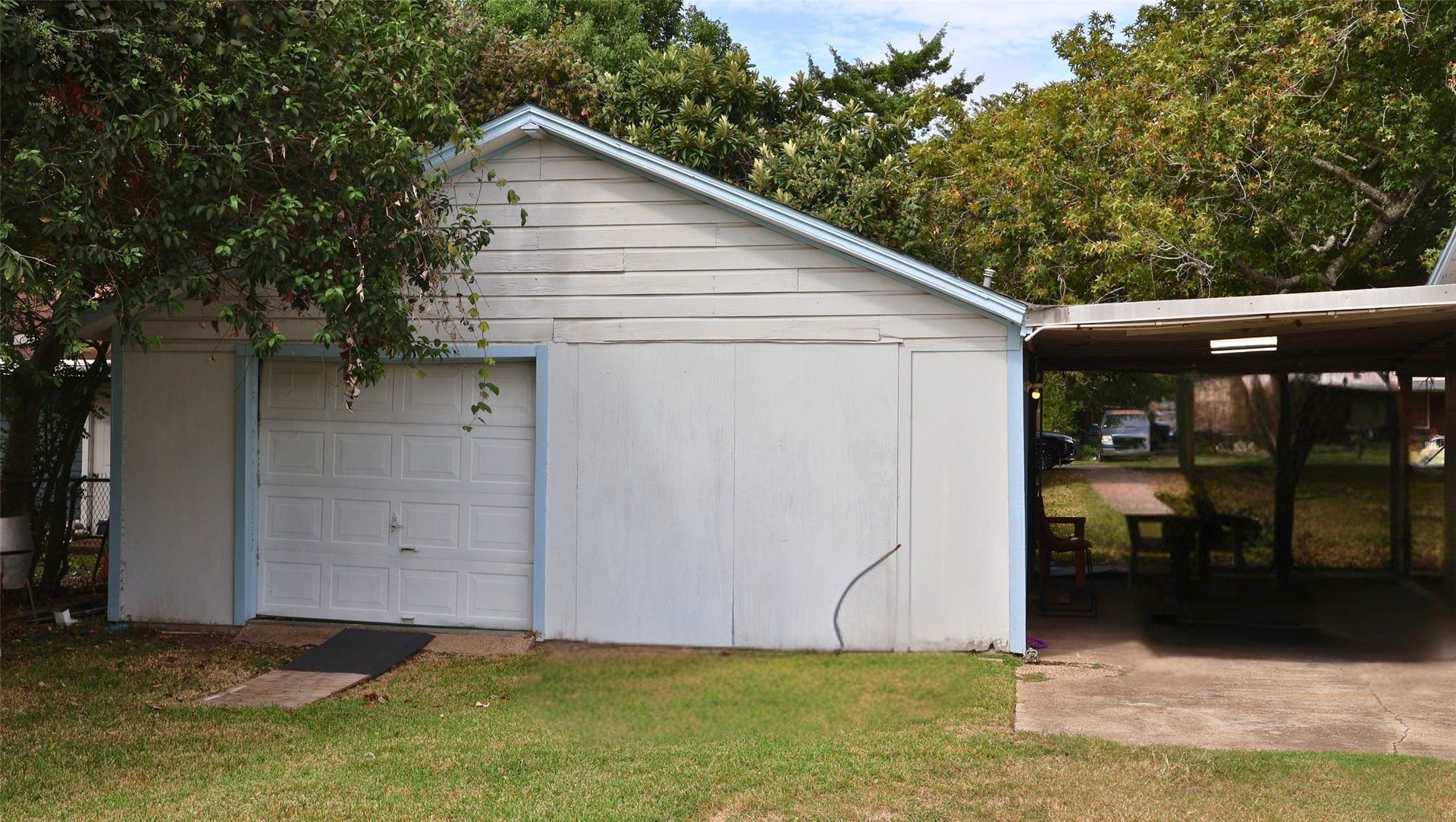 7029 Church Lane, Hitchcock, TX 77563 Spacious detached garage with adjacent covered patio area, nestled among mature trees for added shade and privacy.