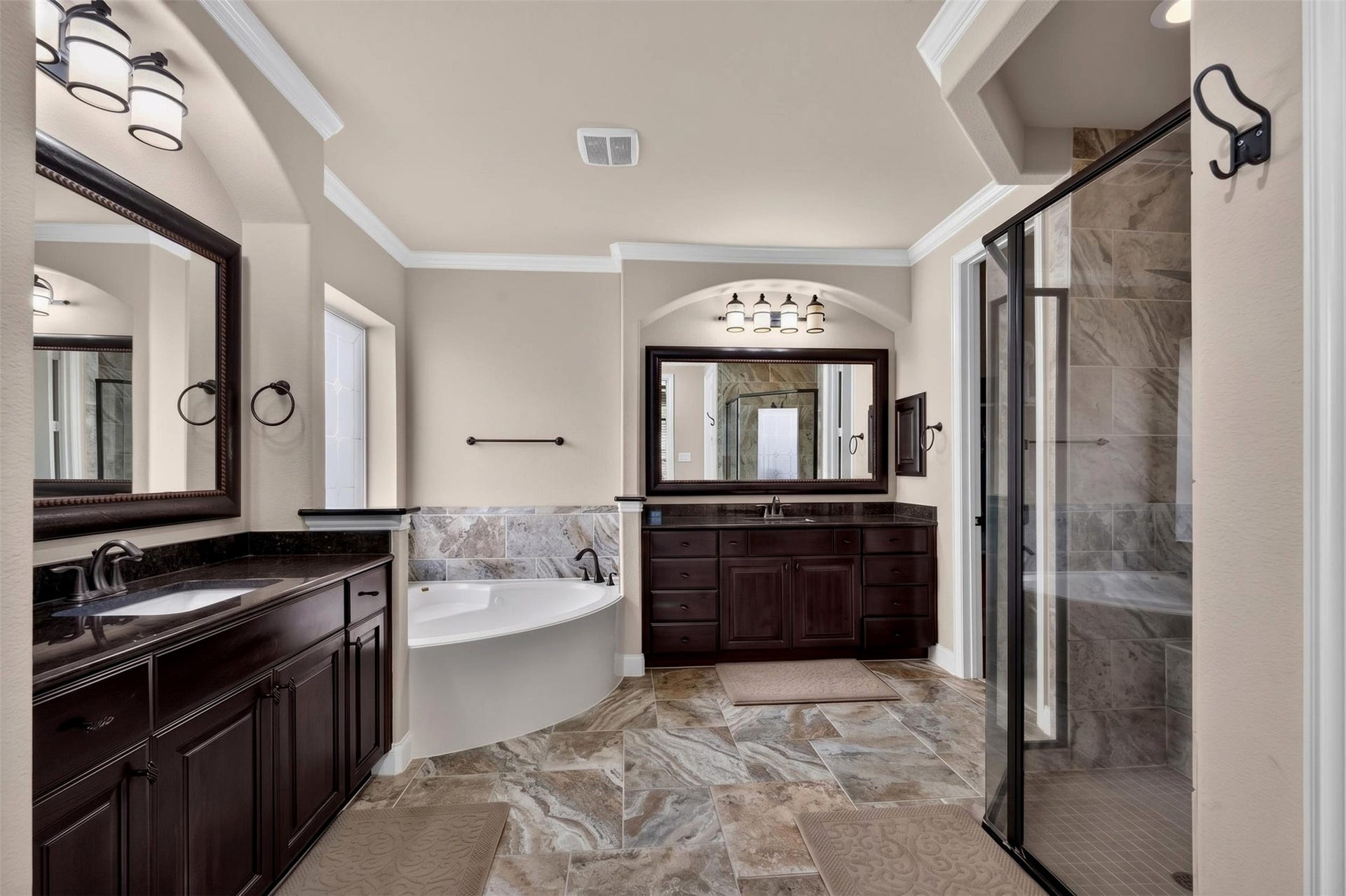 27818 Burchfield Grove Lane, Katy, TX 77494 The primary bathroom welcomes you with rich espresso cabinetry, dark countertops, and framed mirrors that create a polished look. tThe spacious layout provides separate areas for daily routines.