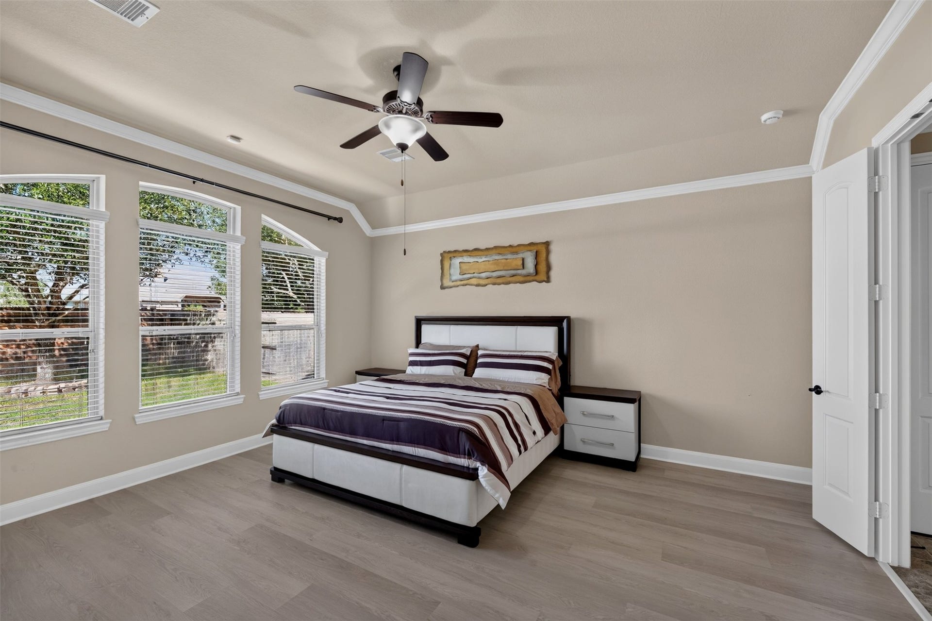 27818 Burchfield Grove Lane, Katy, TX 77494 Step into the spacious primary bedroom, where soft neutral tones and an inviting layout create a comfortable retreat. Three large windows bring in natural light and offer views of the backyard, while the tray ceiling with crown molding adds an elegant finishing touch.