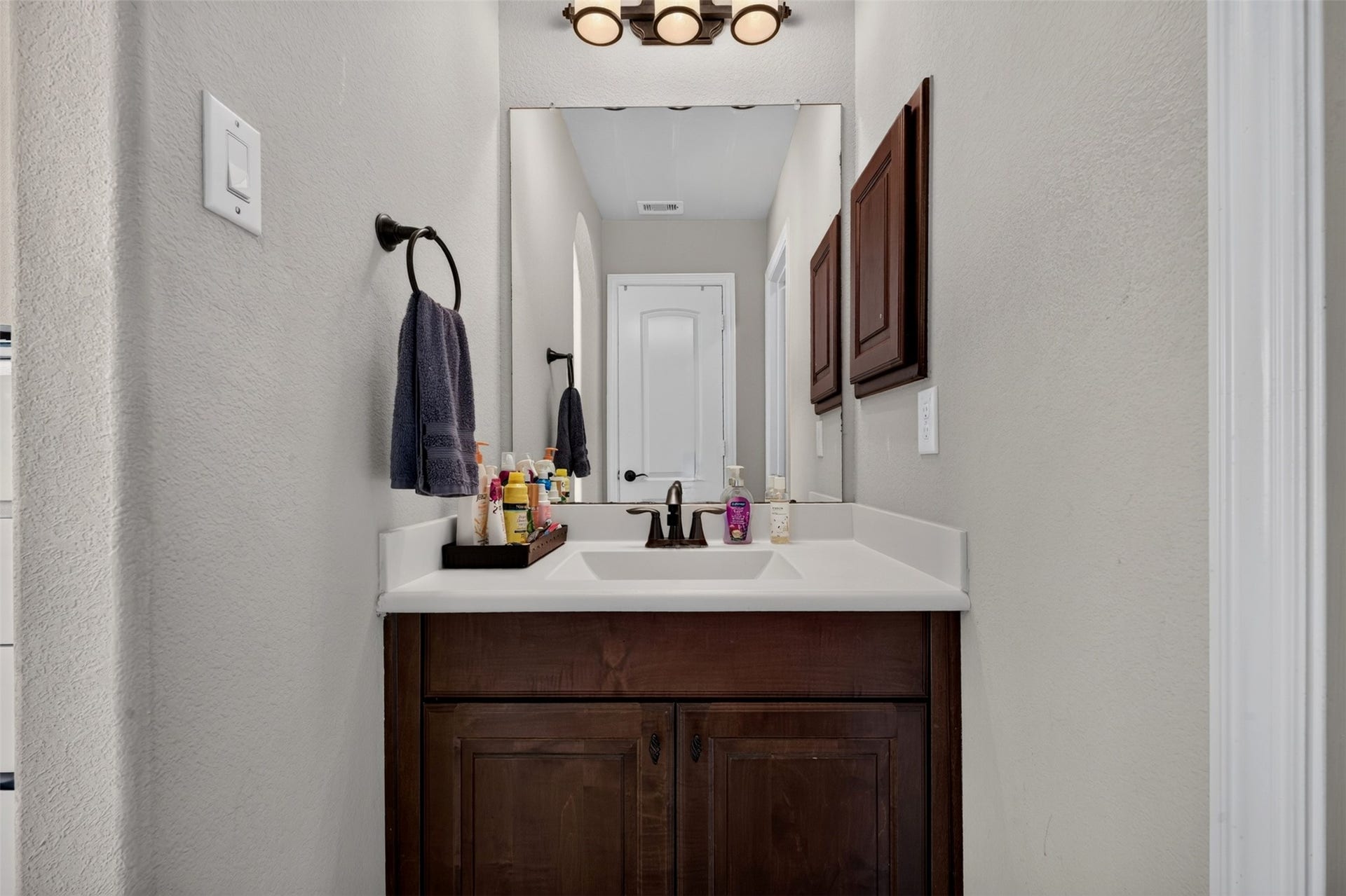 27818 Burchfield Grove Lane, Katy, TX 77494 A generous vanity with a white countertop and rich wood cabinetry offers practical storage and everyday functionality. The large mirror and attractive light fixture complete this well-appointed bathroom space.