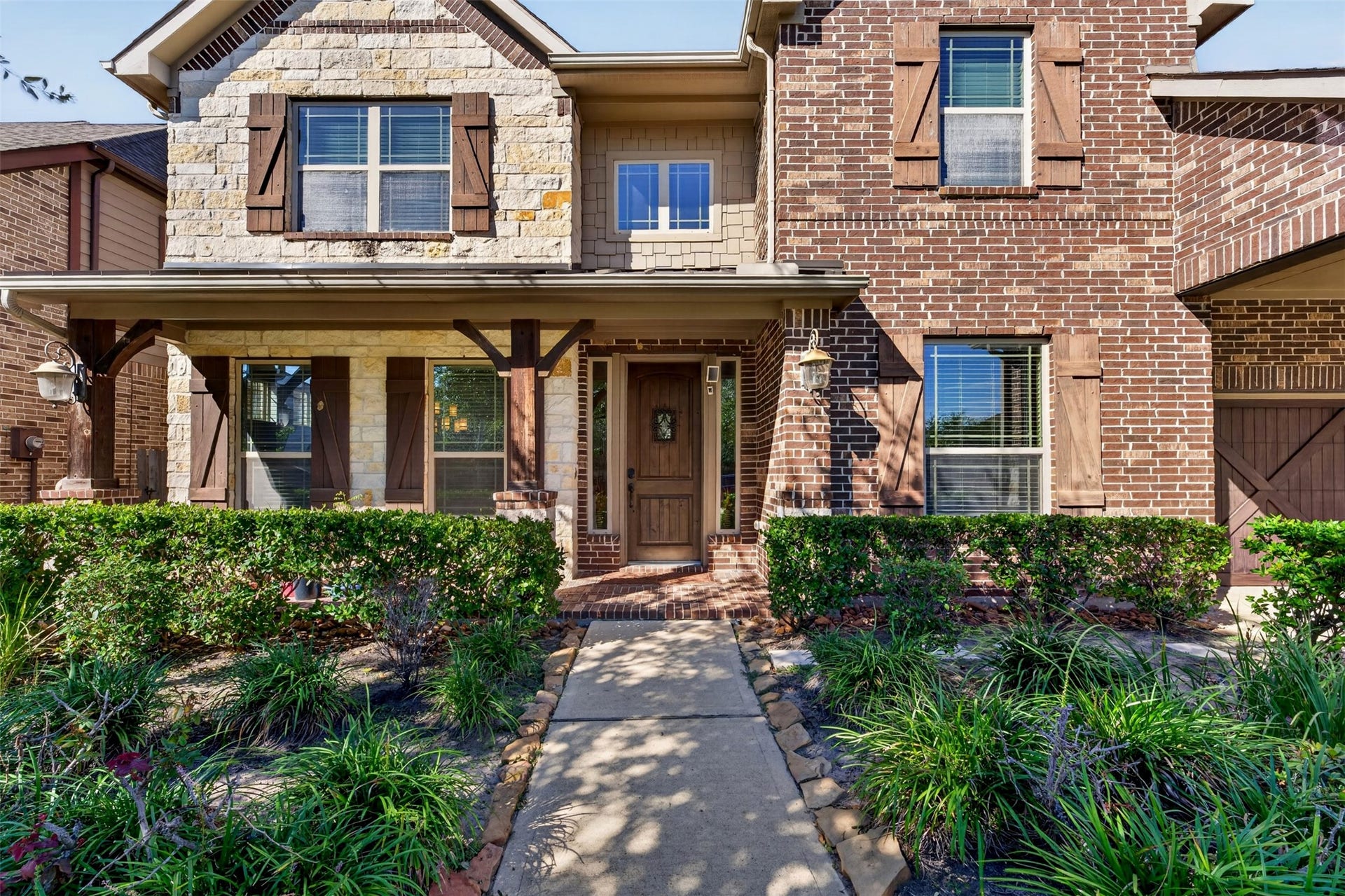27818 Burchfield Grove Lane, Katy, TX 77494 A closer look reveals the inviting front porch, wood entry door, and architectural blend of brick and stone. Thoughtfully arranged landscaping and shaded walkways add to the home's welcoming character.