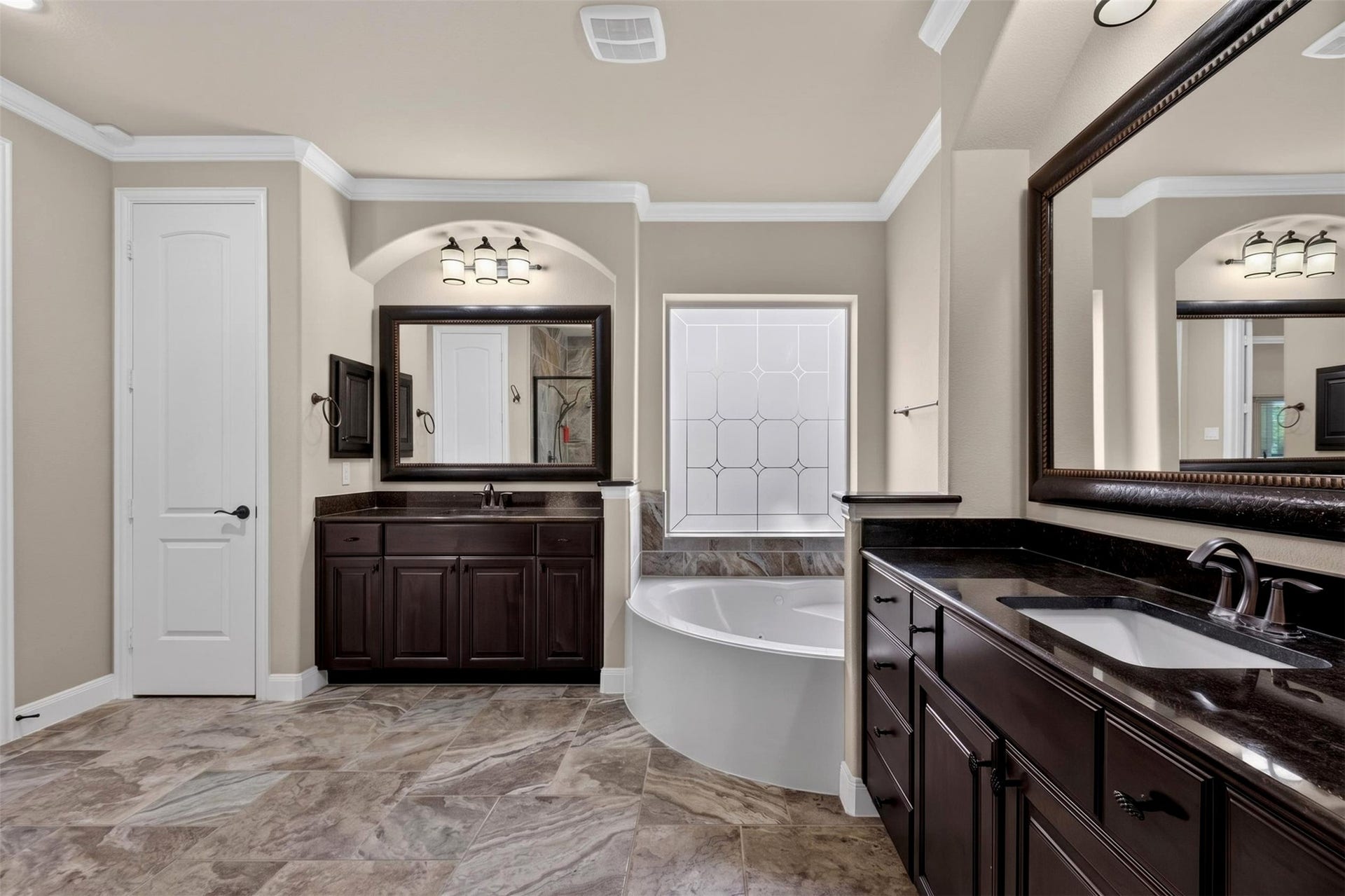 27818 Burchfield Grove Lane, Katy, TX 77494 This alternate view highlights the bathroom's thoughtful arrangement, with dual vanities positioned on opposite sides of the room and the soaking tub nestled between them. Coordinating cabinetry, framed mirrors, and decorative tile create a cohesive appearance throughout.