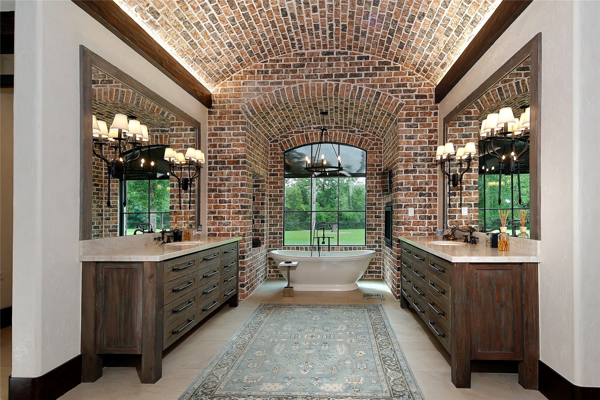 Welcome to your personal spa! Framed by a brick barrel ceiling the free standing soaking tub features a discreetly placed TV, electric wall fireplace and an electric remote-controlled window shade for privacy. Double vanities and quartzite countertops, a coffee bar with a fridge and a huge walk in shower with double heads. In addition a washer and dryer for your personal laundry.