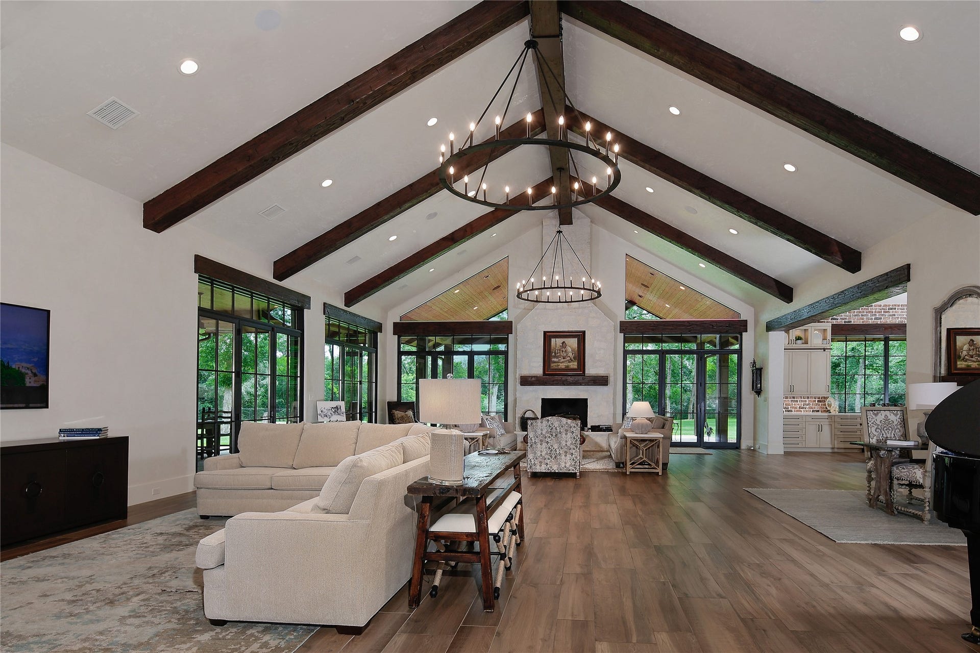 The open concept welcomes friends and family into this impressive room. With a 20 foot ceiling, exposed wood beams and anchored by a stone two story remote controlled fireplace. The French doors open to a sprawling wrap around back patio area extending your entertaining space.