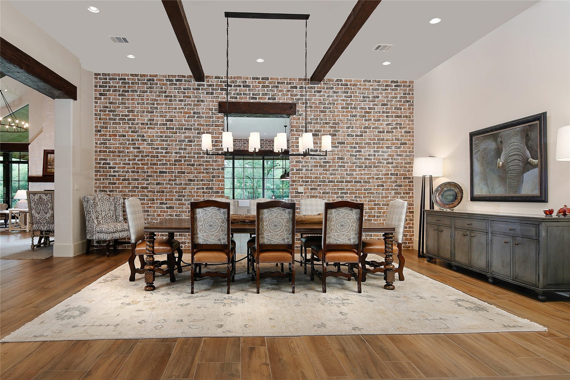 The great room flows into the dining room featuring a brick accent wall and modern lighting.